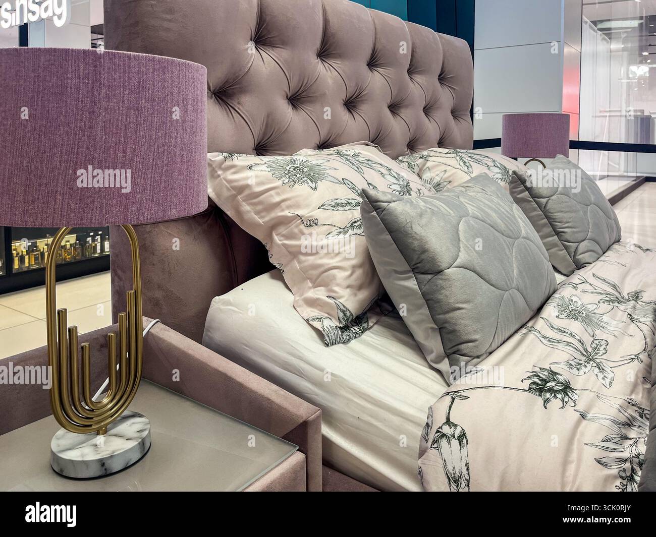 Accogliente camera da letto con testiera a bottone, cuscini decorativi e lampade eleganti, che presentano un'atmosfera calda perfetta per notti riposanti e relax Foto Stock