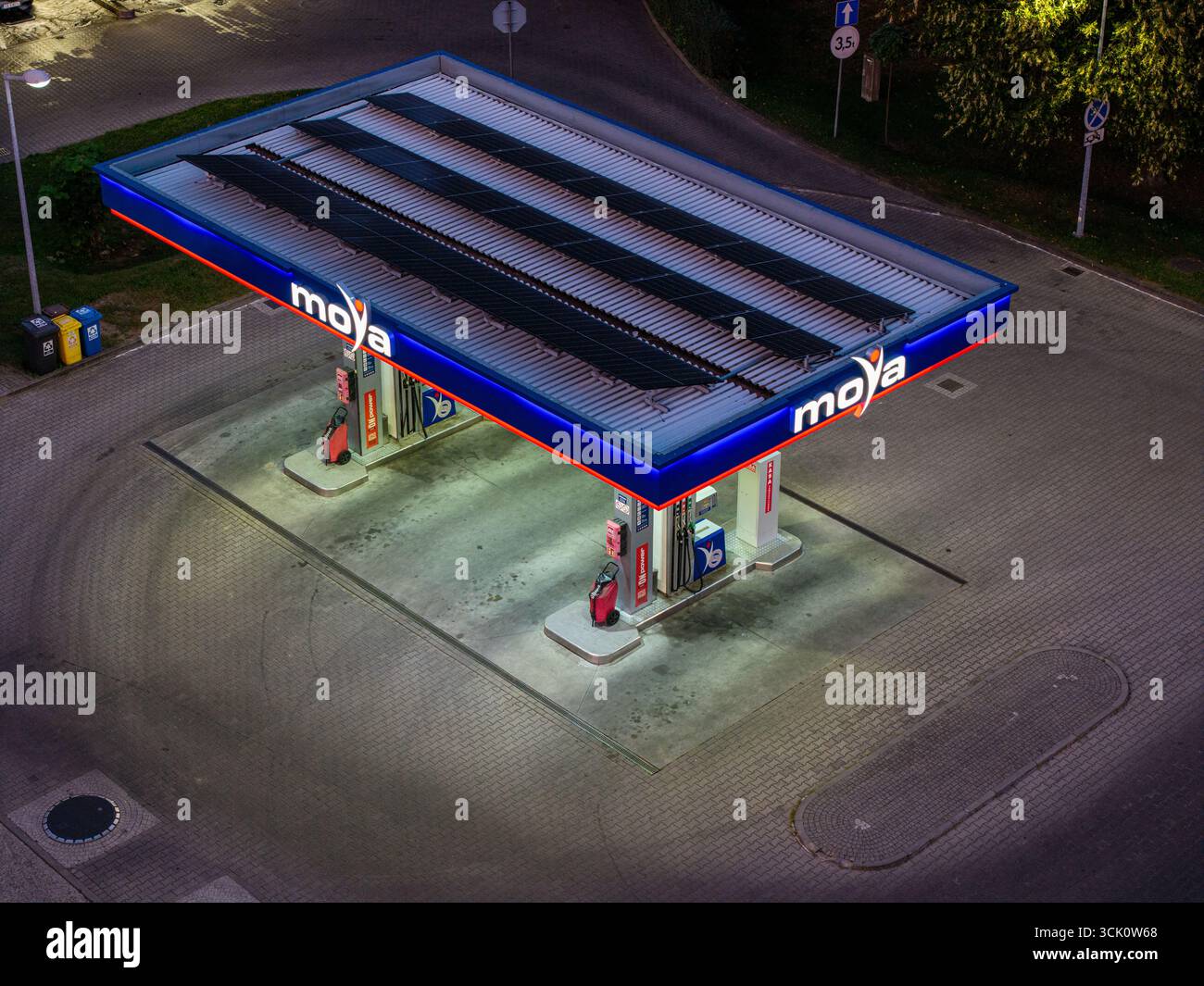 Distributore di benzina MOYA di notte, vista aerea con droni, tettoia a strisce blu, illuminazione vivida, auto singola, disposizione orizzontale, eccellente per carburante, marchio e u Foto Stock