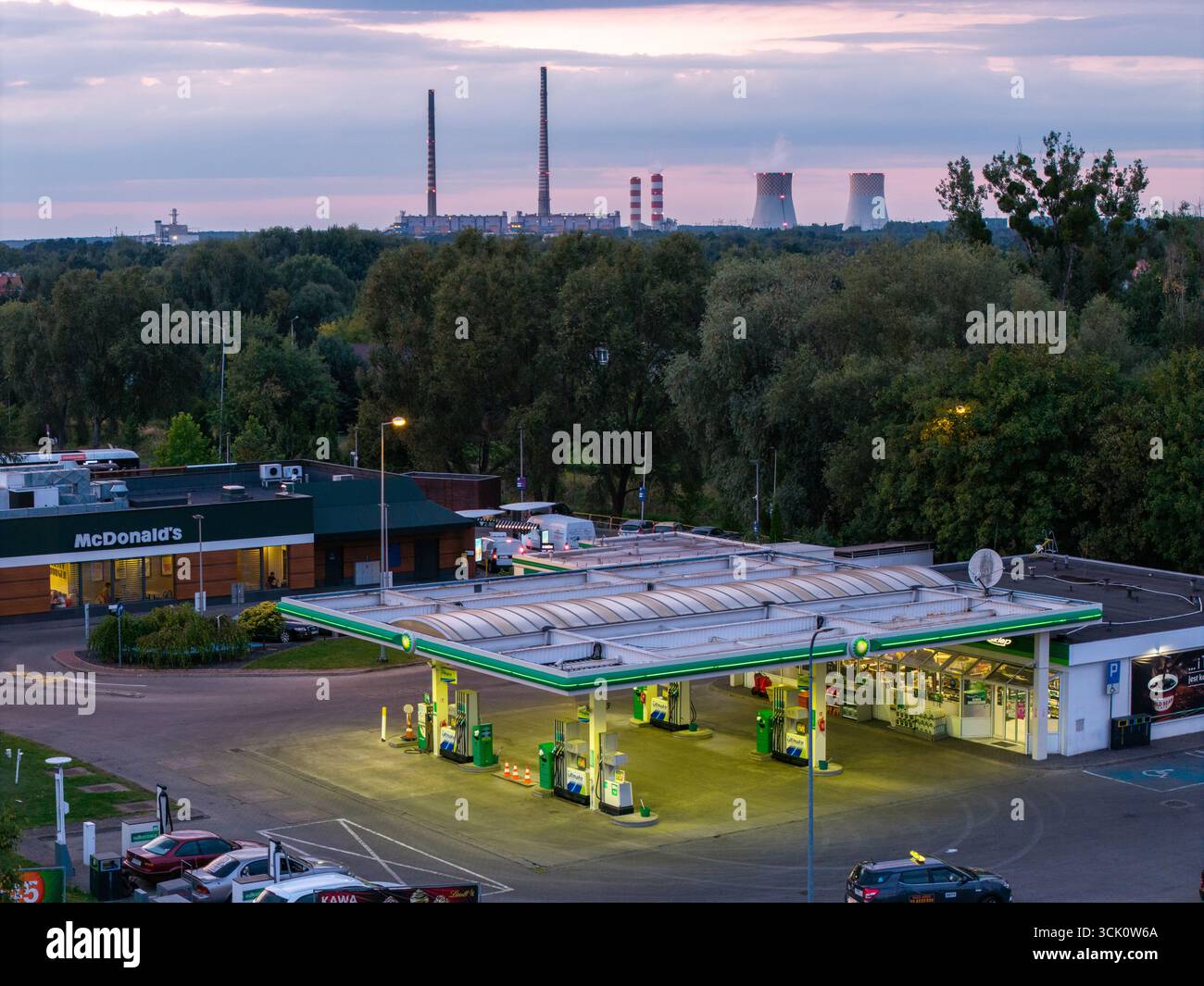 Foto aerea di un moderno distributore di benzina con McDonald's al tramonto, illuminazione vivace, vista panoramica, primo piano urbano, ideale per attività commerciali, viaggio, Foto Stock