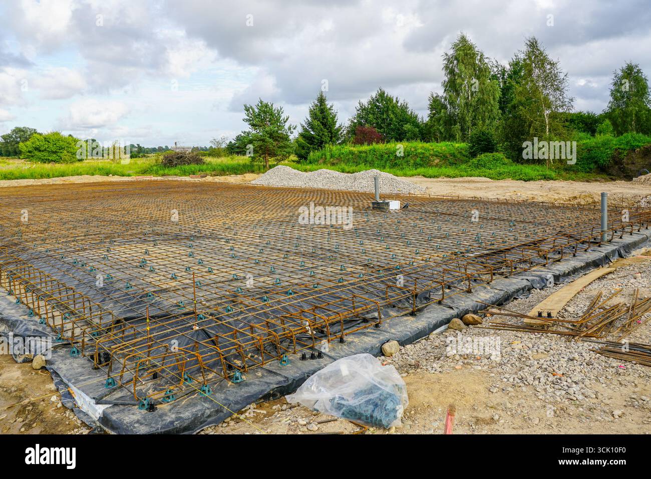 Griglia a rete in acciaio rinforzato installata per versare solette di fondazione in calcestruzzo nel cantiere, materiali da costruzione visibili Foto Stock