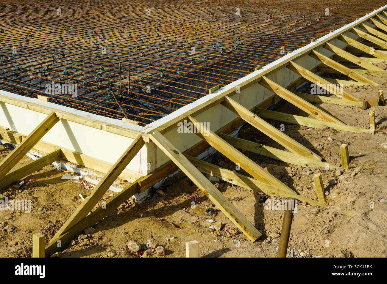 Vista dettagliata delle fondamenta a griglia per tondini in acciaio rinforzato con isolamento termico e rinforzi in legno per casseforme predisposti per il travaso di solette in cemento Foto Stock
