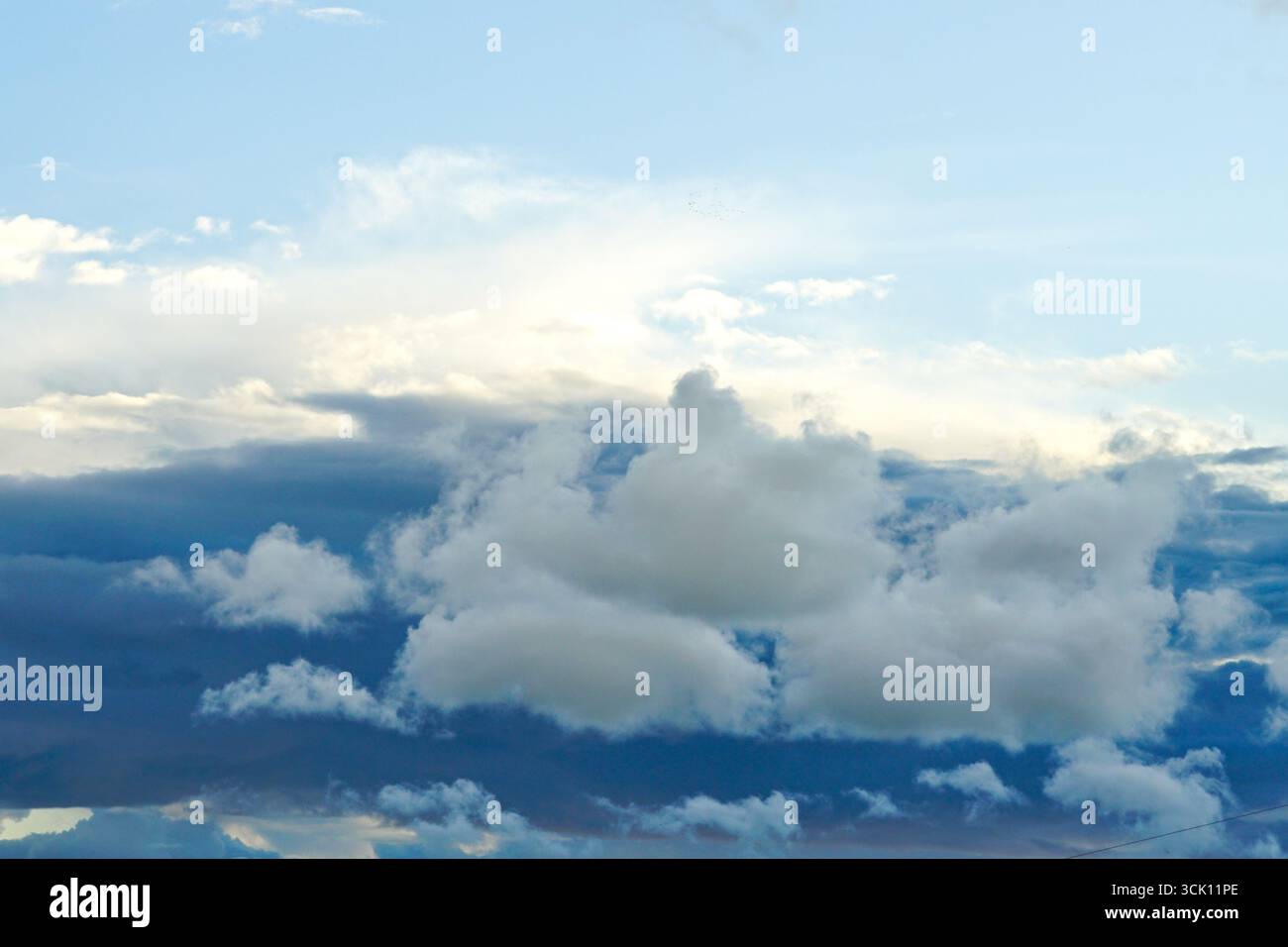 Cielo bellissimo con nuvole bianche di cumulus e nuvole di tempesta più scure al tramonto, creando un paesaggio naturale drammatico e lunare Foto Stock