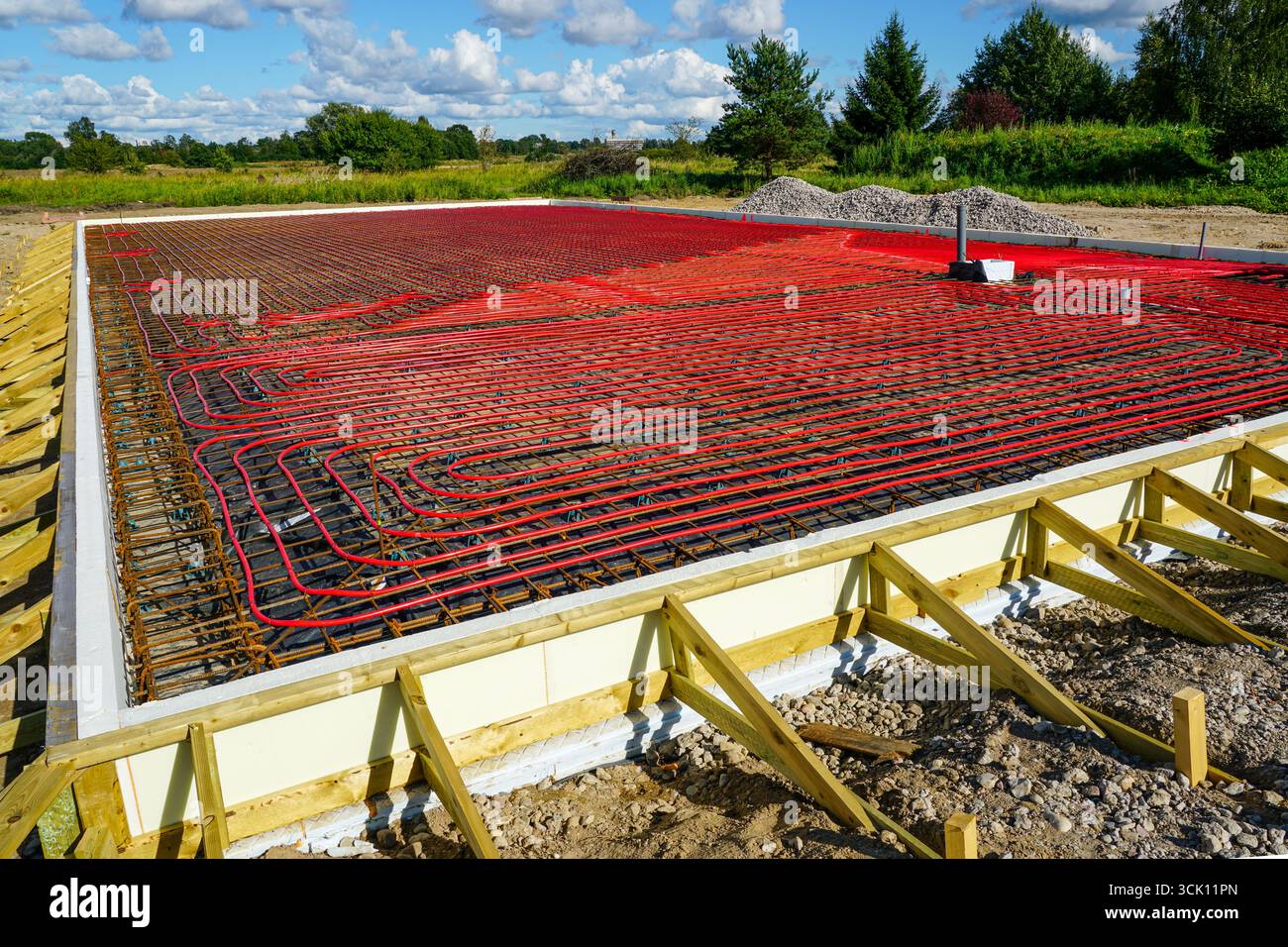 Fondazioni in calcestruzzo isolate con tubi di riscaldamento a pavimento rossi e rinforzo in acciaio predisposti per il versamento in cantieri edili residenziali Foto Stock