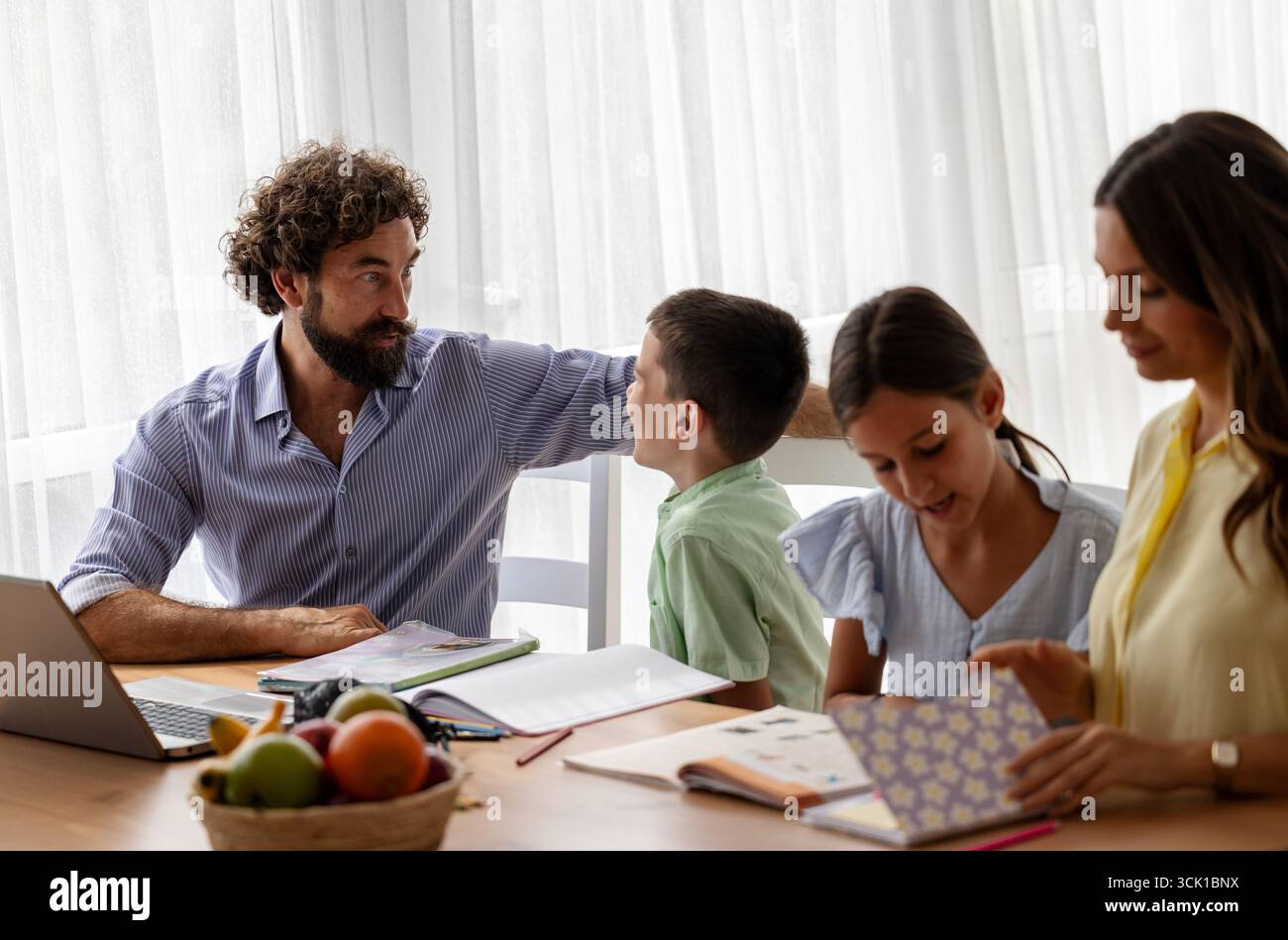 La famiglia si riunisce intorno a tavola, impegnandosi in attività educative. I genitori assistono i loro figli con i compiti mentre si godono del tempo di qualità Foto Stock