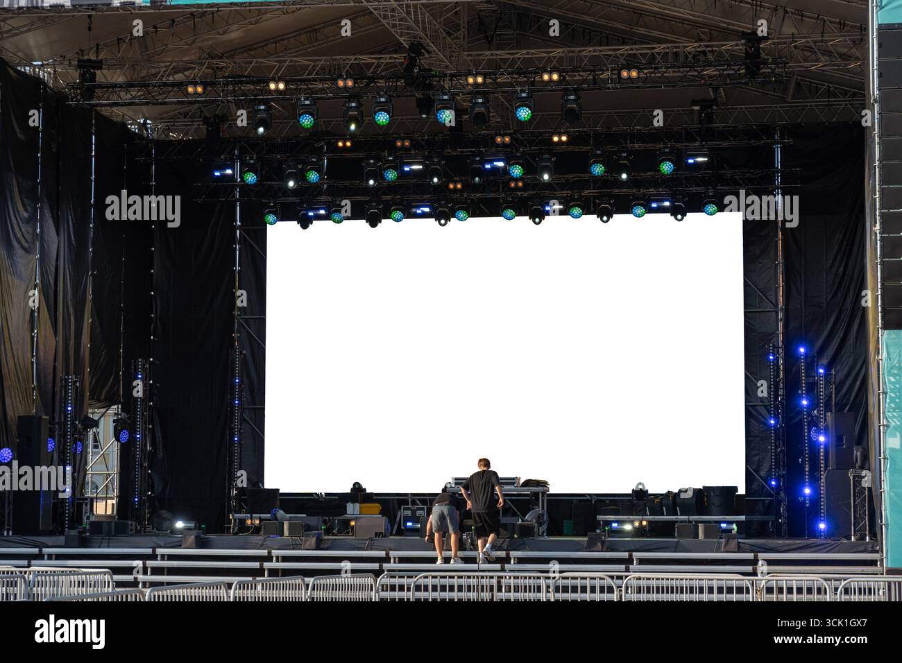 La troupe di palcoscenico prepara la produzione di concerti con un enorme schermo a LED, sistemi audio e di illuminazione per un evento dal vivo. Foto Stock