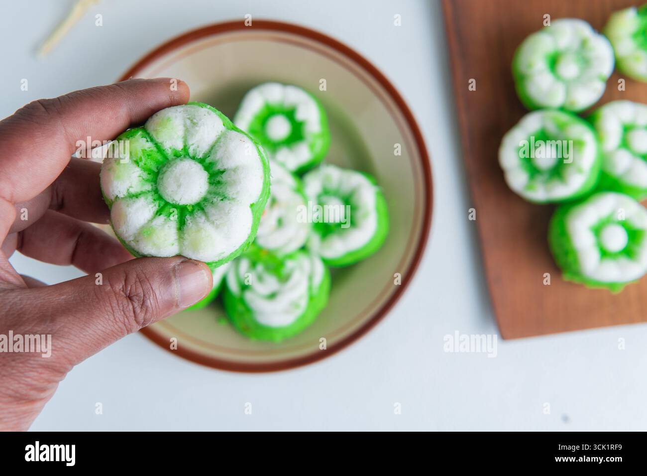 Tenendo a mano una tradizionale torta indonesiana al vapore chiamata putu ayu, sapore di pandan con condimento di cocco grattugiato, morbido e dolce. Foto Stock