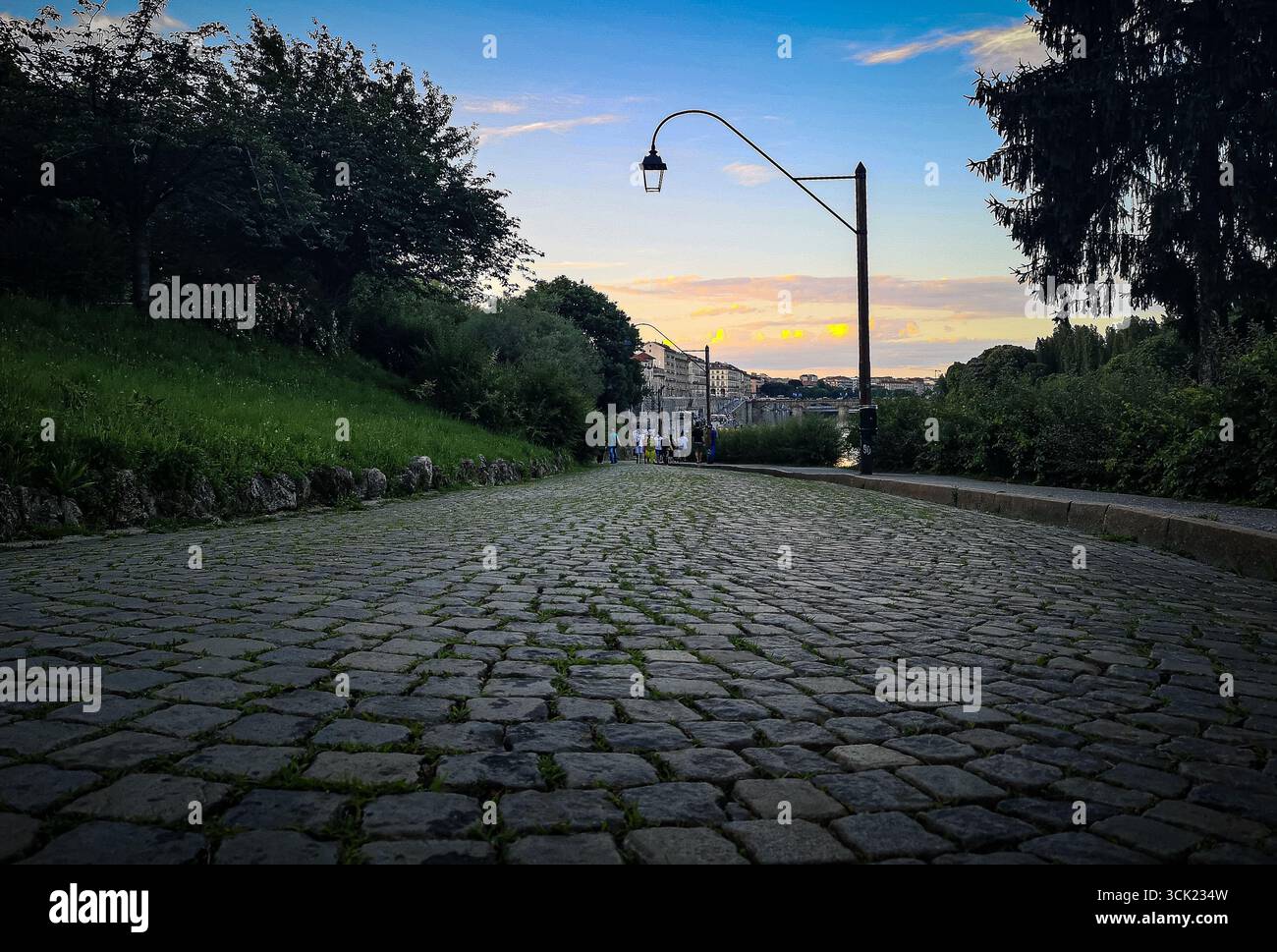 Un grandangolo di un classico sentiero acciottolato a Torino, in Italia, al crepuscolo. L'immagine evidenzia la trama dettagliata del tracciato, con una traditiona - Immagine stock catturata con smartphone