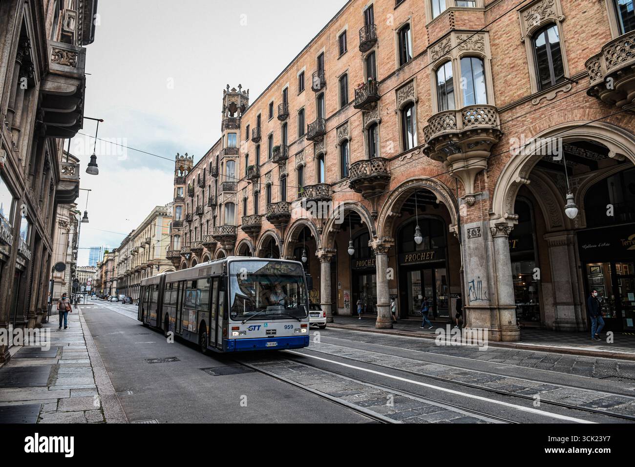 Una vista a livello della strada di un autobus pubblico su una strada acciottolata a Torino, Italia. La fotografia mostra il paesaggio urbano storico della città, con cla Foto Stock