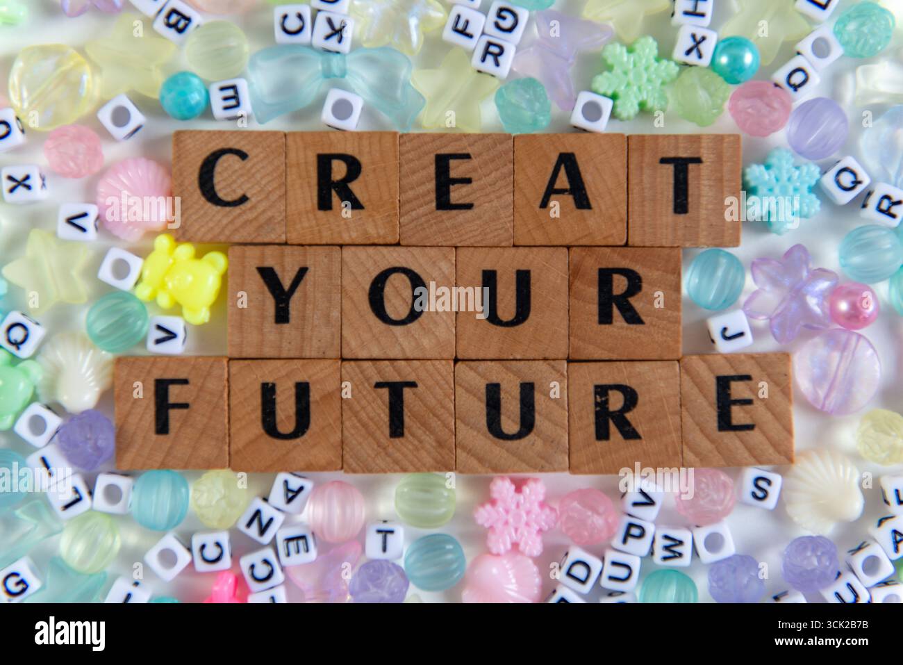 Frase ispiratrice "Creat Your Future" con piastrelle di legno, circondate da perline pastello e lettere di plastica. Un appartamento creativo e motivazionale Foto Stock
