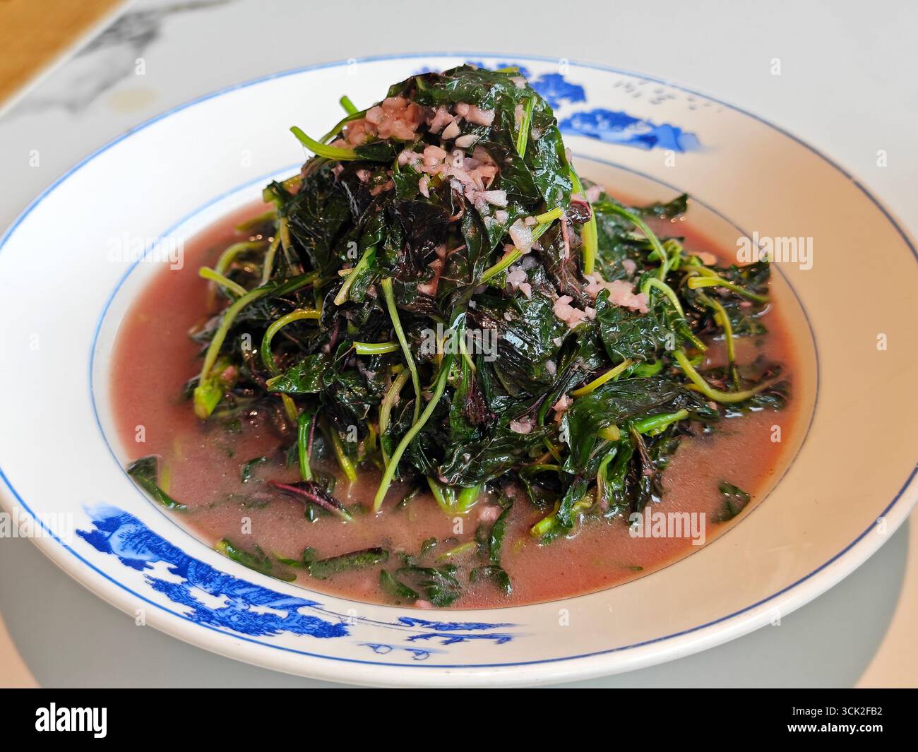 Amaranto fresco strapazzato con aglio nel piatto per mangiare Foto Stock