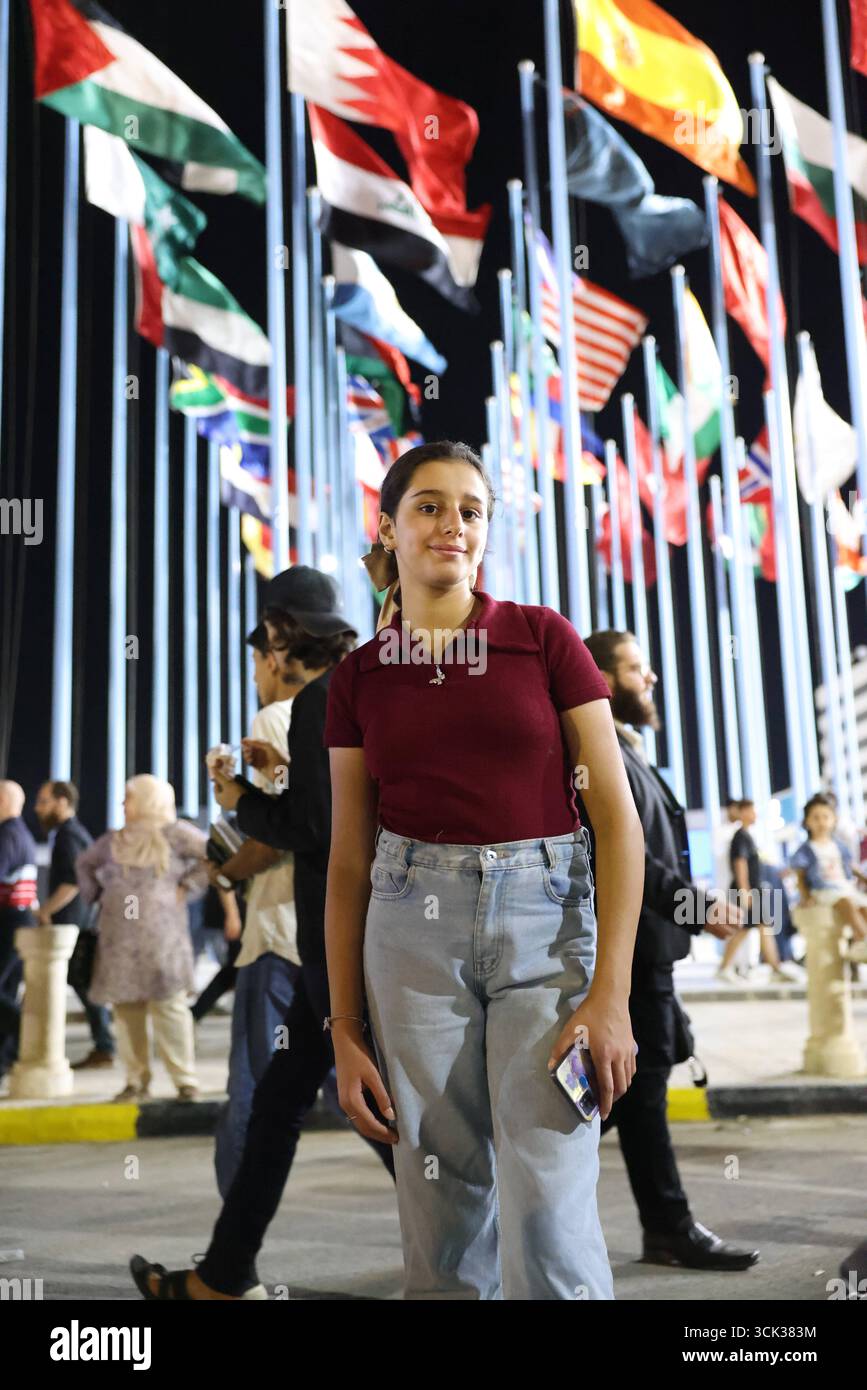 Bandiere di 22 Paesi partecipanti esposte alla Fiera Internazionale di Damasco. I visitatori scattano foto ricordo nella piazza centrale della Fiera Internazionale di Damasco, con le bandiere di 22 paesi partecipanti esposte sullo sfondo. La fiera, che si tenne dopo la caduta del regime di Assads, attirò grandi folle esplorando mostre culturali ed economiche. Damasco Siria Copyright: XMohammadxBashirxAldaherx Foto Stock
