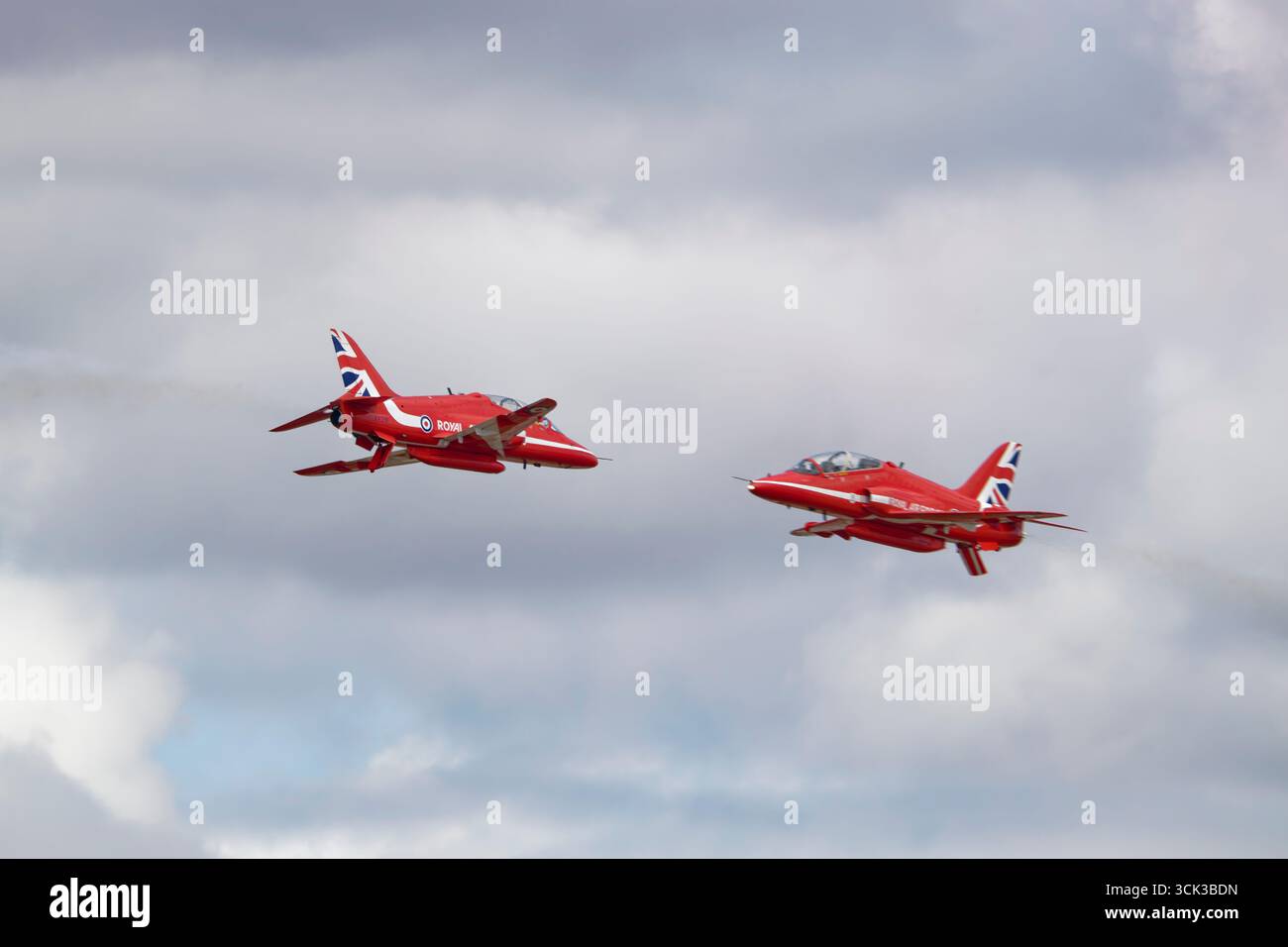 Due BAE Hawk Advanced Jet Trainers della RAF Red Arrows eseguono un rischioso e ravvicinato passaggio di opposizione durante il Royal International Air Tattoo. Foto Stock