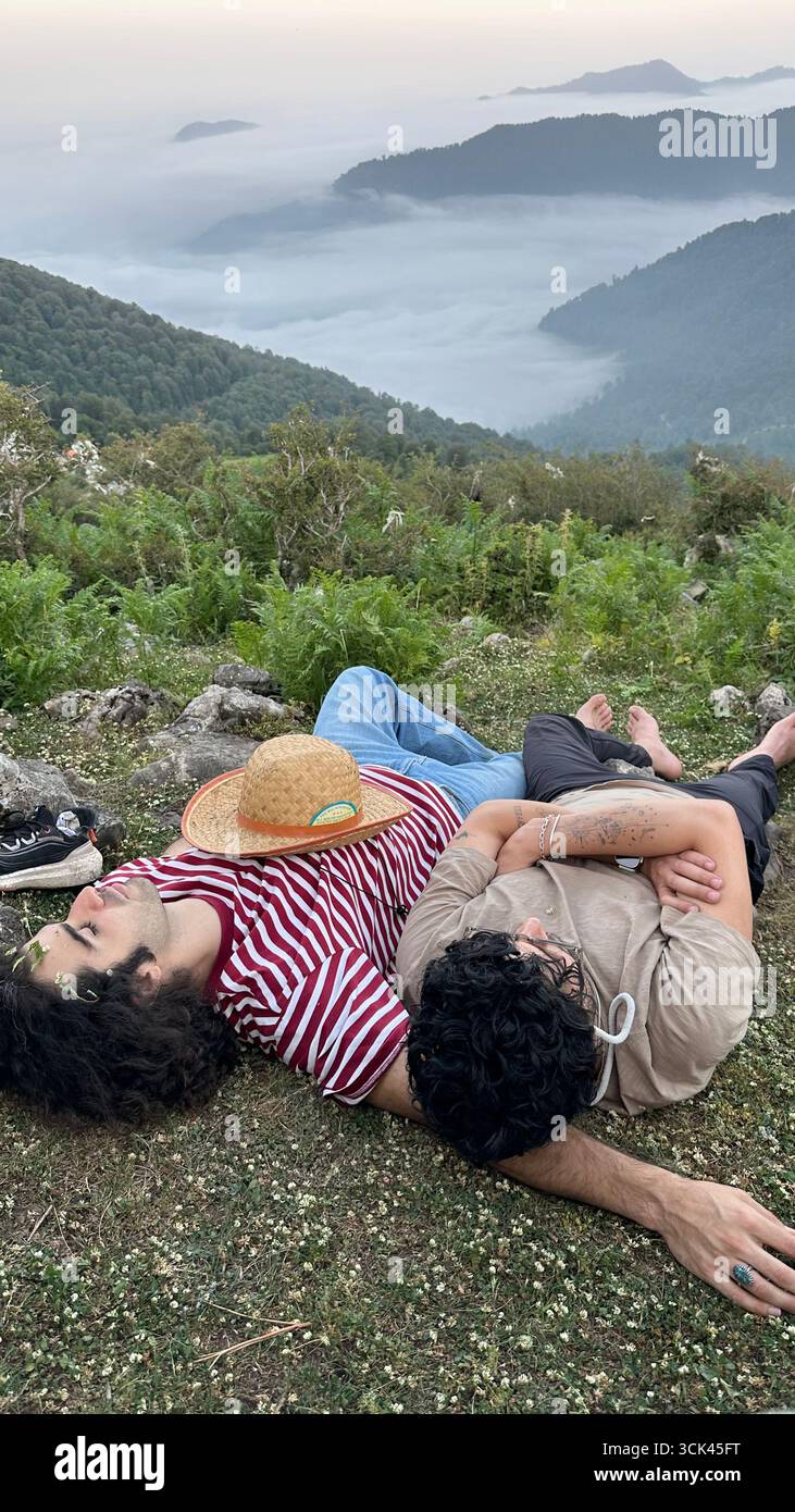 Un tranquillo riposo sulla cima di una montagna, che si affaccia su una valle di nuvole. Due amici trovano pace e amicizia in mezzo al paesaggio nebbioso. - Immagine stock catturata con smartphone