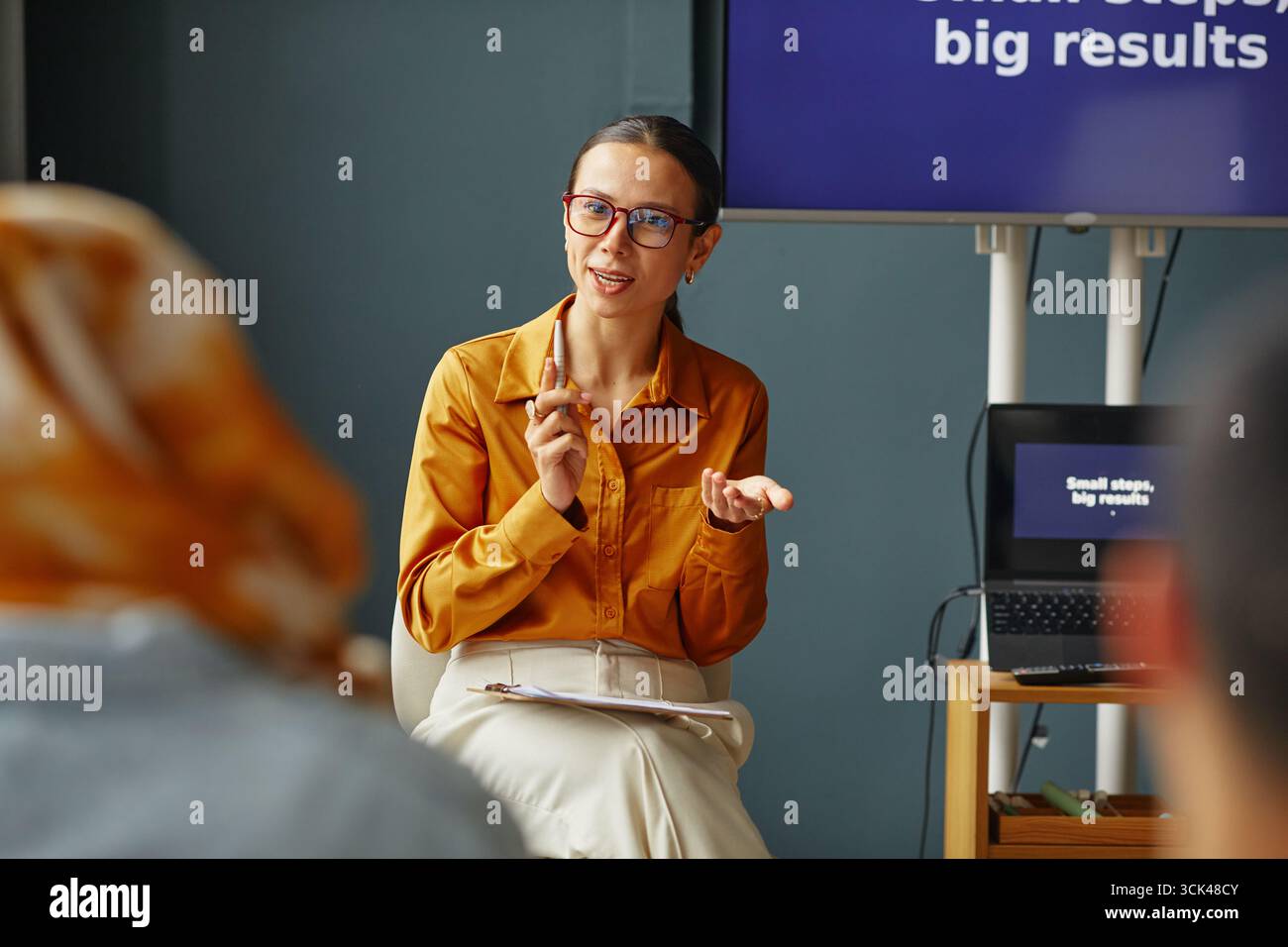 Giovane donna adulta caucasica che spiega i concetti linguistici durante la lezione scolastica Foto Stock