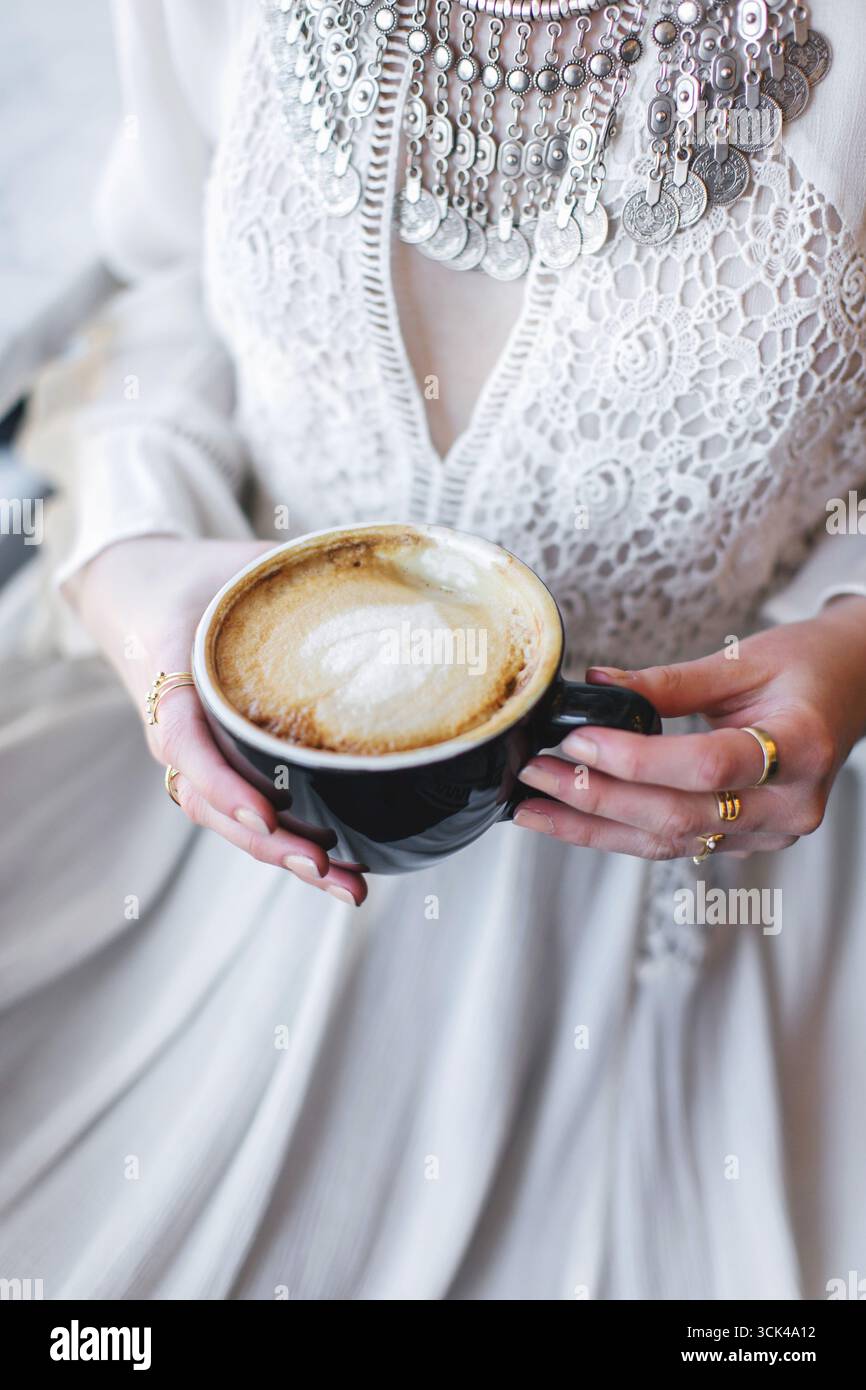 Cappuccino con motivo a base di schiuma di latte nelle mani delle donne Foto Stock