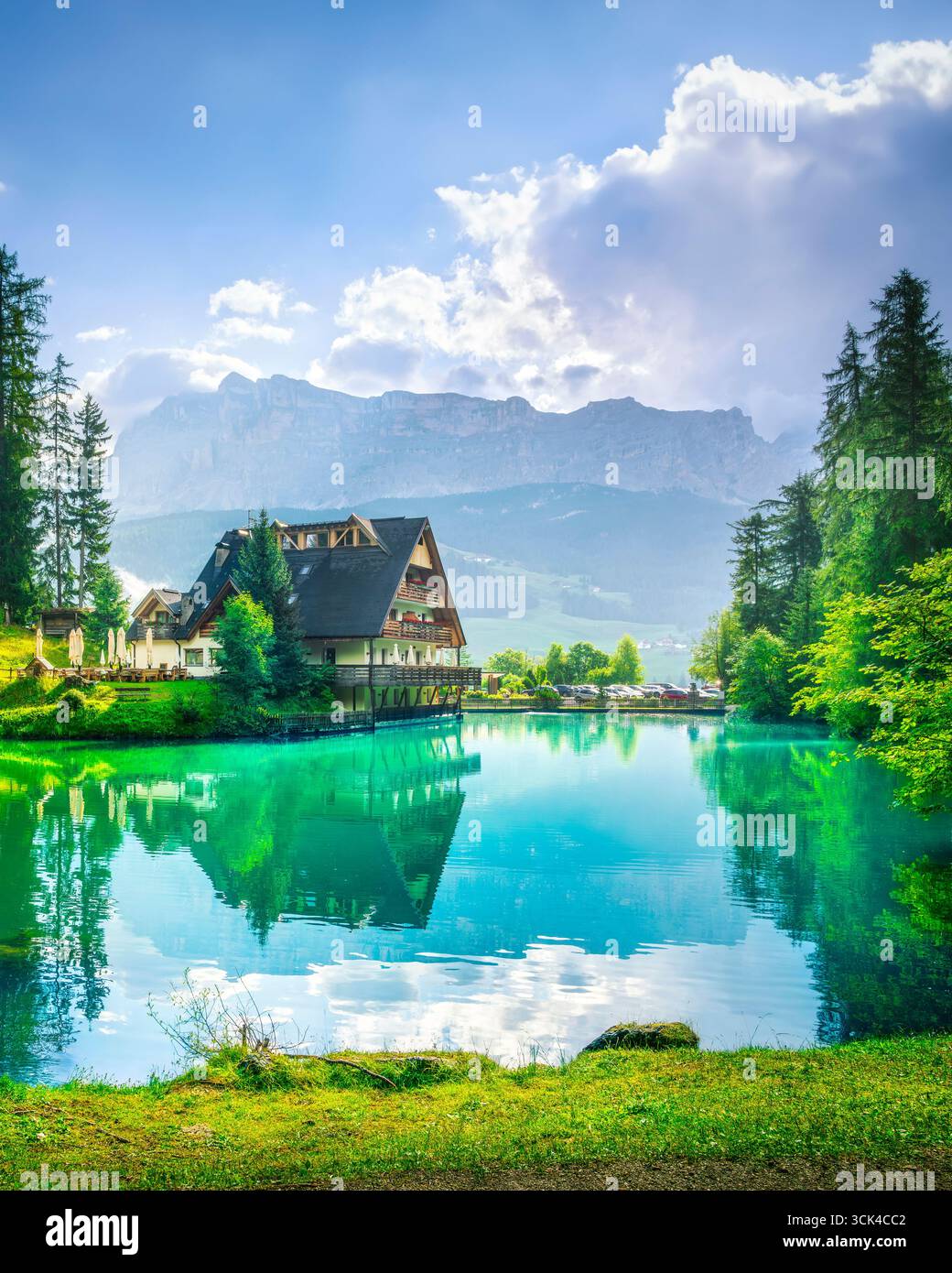 Lago panoramico Sompunt con acque cristalline color smeraldo che riflettono le tradizionali case alpine e la lussureggiante foresta nella valle di Badia, sito UNESCO delle Dolomiti, Sout Foto Stock