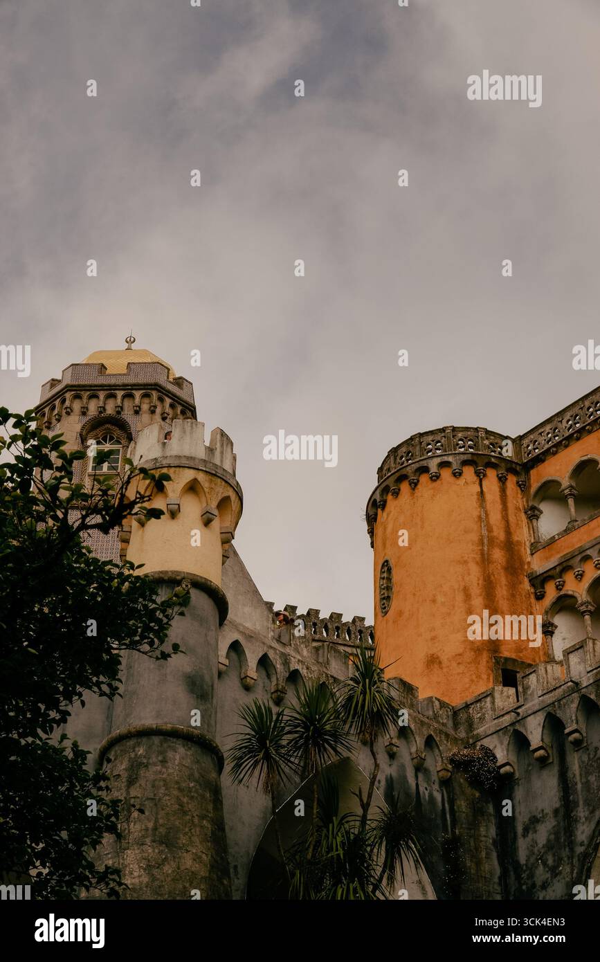 Vista architettonica del Palácio da pena a Sintra, Portogallo, con la sua cupola dorata, torri cilindriche gialle, contro un cielo nuvoloso. Foto Stock