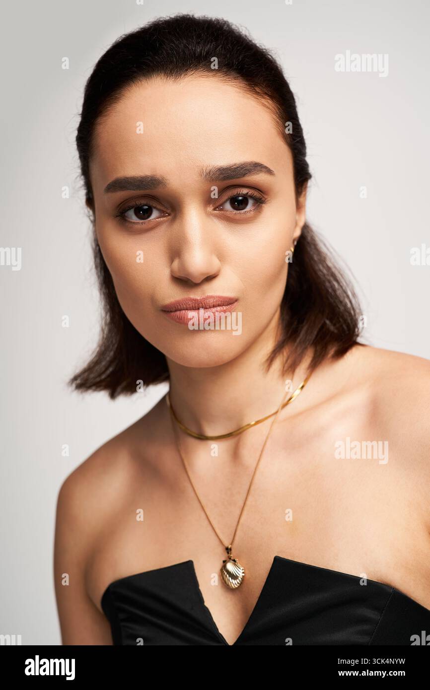 Una giovane donna indossa con sicurezza un abito nero alla moda, trasudando eleganza e grazia. Foto Stock