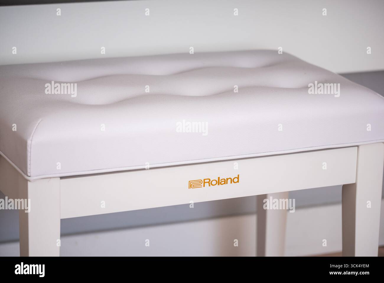 Riga, Lettonia - 4 settembre 2025: Roland, elegante sgabello bianco con un cuscino trapuntato, progettato per il comfort e l'eleganza, ideale per l'ambiente musicale Foto Stock