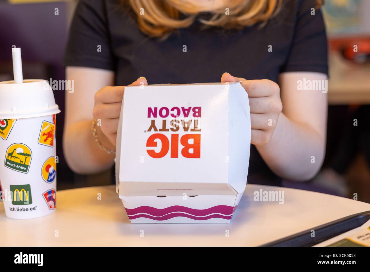 Kerpen, Germania - 9 agosto 2025: Hands Holding Big Tasty Bacon Burger Box in McDonalds Foto Stock