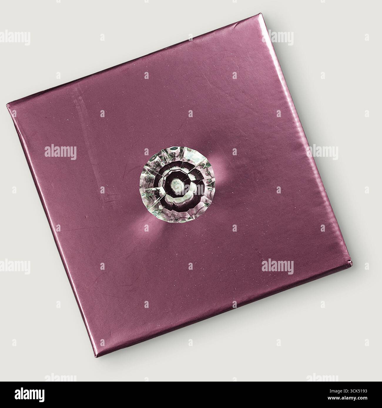 Una scatola regalo viola lucida decorata con un bottone decorativo, perfetta per le occasioni speciali. Foto Stock