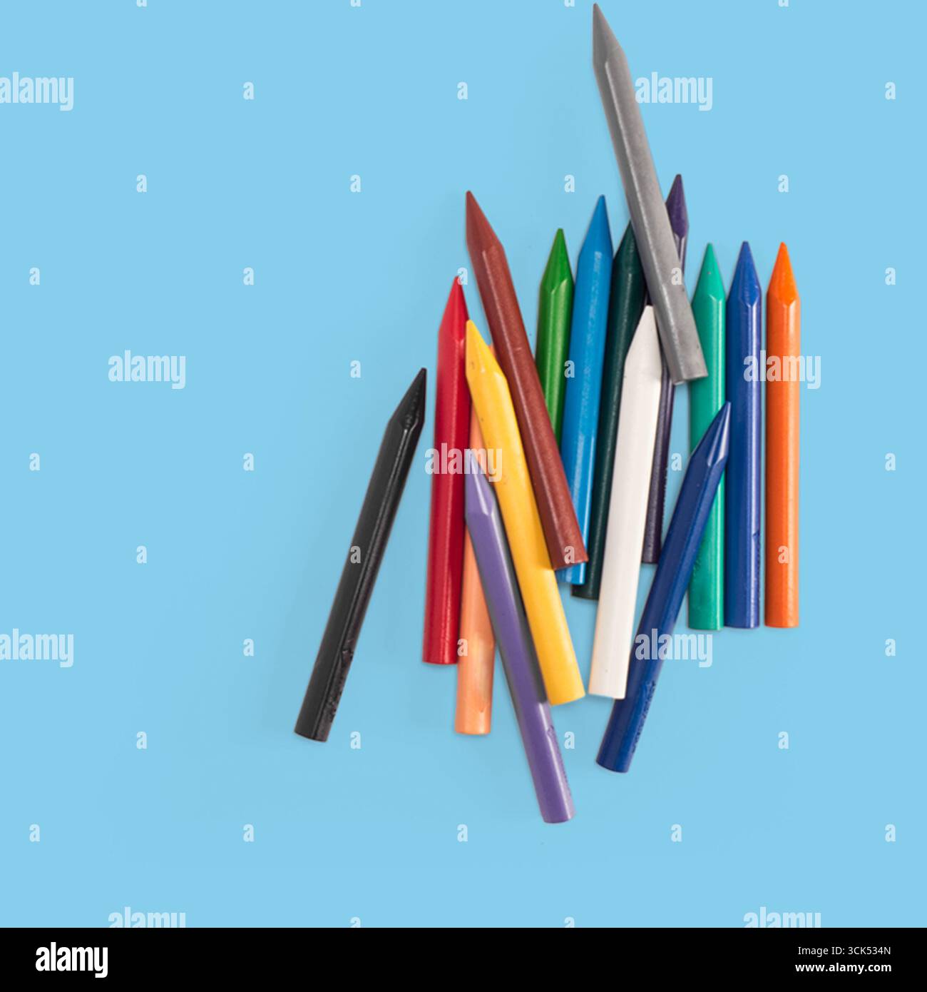 Una collezione di pastelli colorati sparsi su una superficie, ideale per disegnare e attività creative. Foto Stock