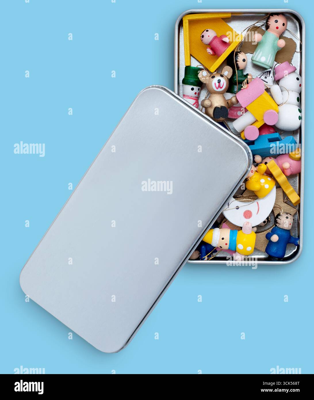 Una teglia di metallo piena di giocattoli colorati e piccole figure, che mostra un assortimento giocoso per attività creative. Foto Stock