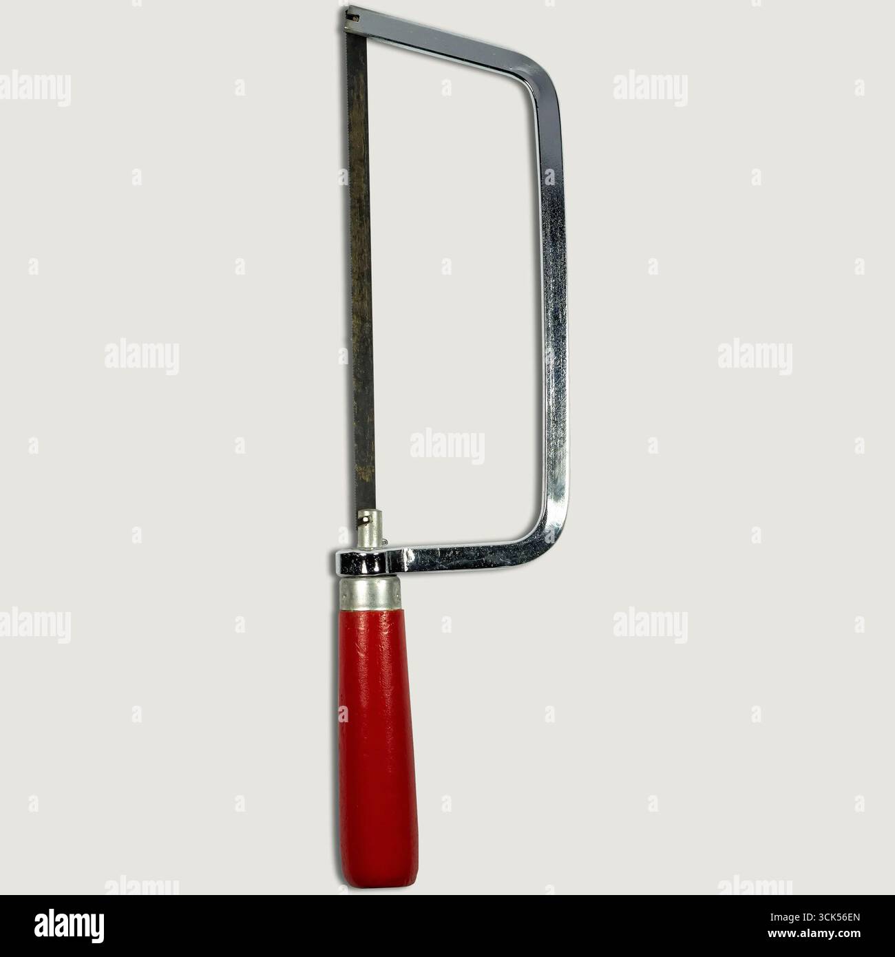 Un seghetto metallico con impugnatura rossa, utilizzato per tagliare vari materiali. Foto Stock