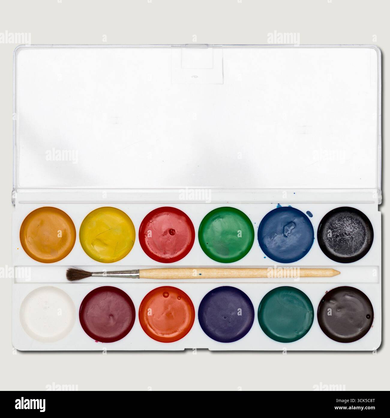 Un set di colori ad acquerello con dodici colori e un pennello, ideale per progetti artistici ed espressioni creative. Foto Stock