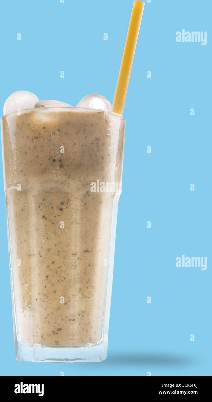 Un bicchiere alto riempito con una cremosa bevanda miscelata, ricoperto di ghiaccio e paglia gialla, perfetto per una bevanda rinfrescante. Foto Stock