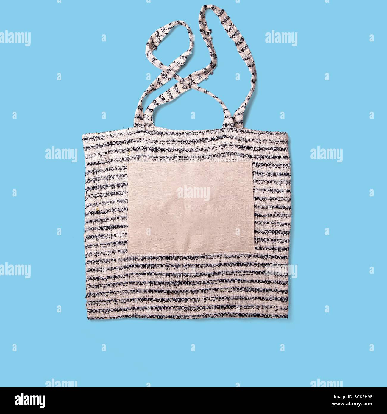 Una borsa tote a righe con una toppa quadrata semplice, progettata per trasportare comodamente gli oggetti. Foto Stock