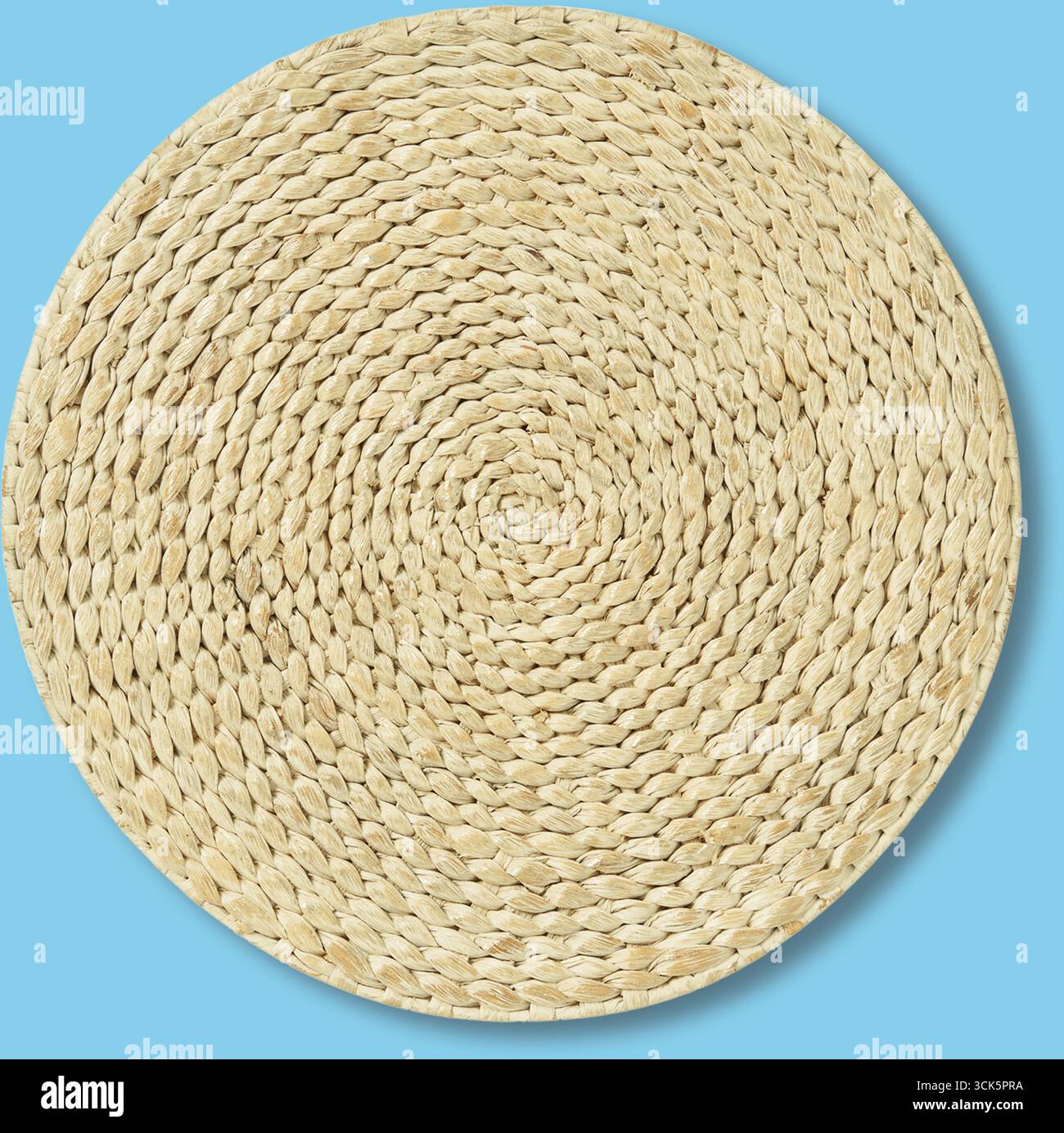 Un tappetino rotondo in tessuto realizzato in fibre naturali, adatto per l'arredamento della casa o come accento decorativo. Foto Stock