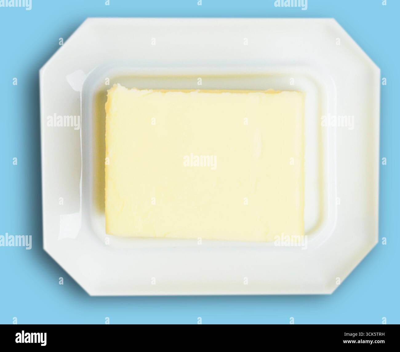 Un blocco di burro posto su un piatto bianco rettangolare. Foto Stock