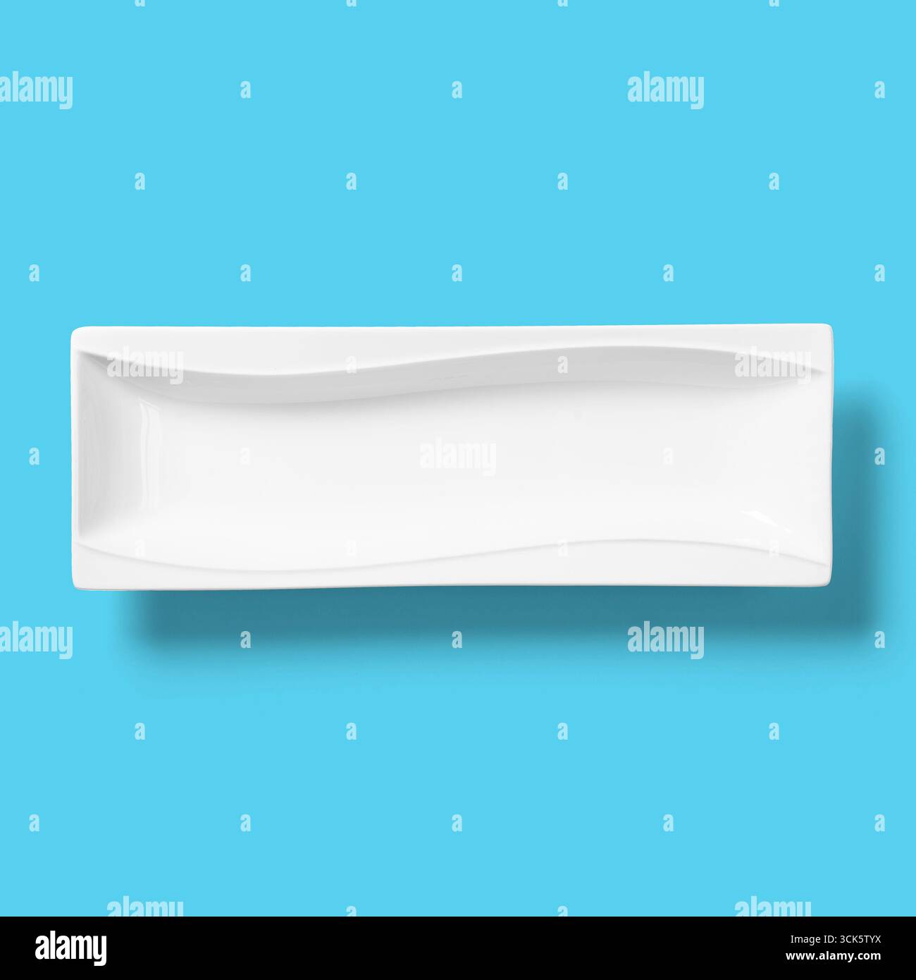 Un piatto rettangolare bianco dal design ondulato, ideale per servire antipasti o sushi. Foto Stock