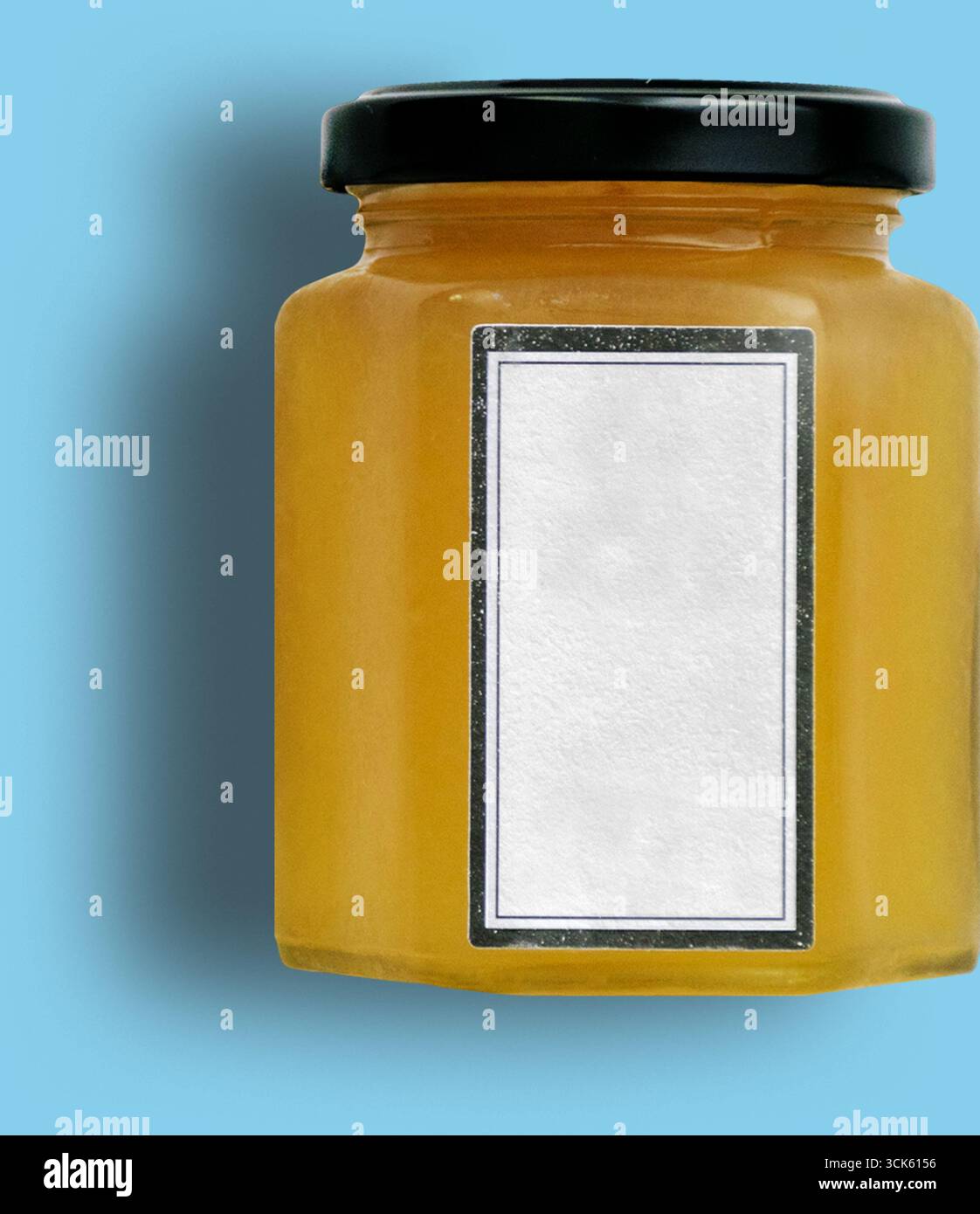 Un recipiente trasparente riempito con una sostanza dorata, probabilmente miele o sciroppo, con un'etichetta vuota per la personalizzazione. Foto Stock