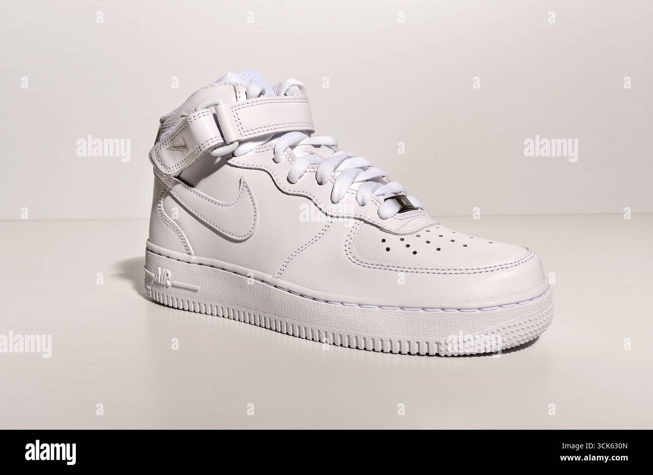 Milano, Lombardia, Italia - 1 settembre 2025: Sneaker alta bianca Nike Air Force 1 con cinturino appoggiato su sfondo bianco Foto Stock