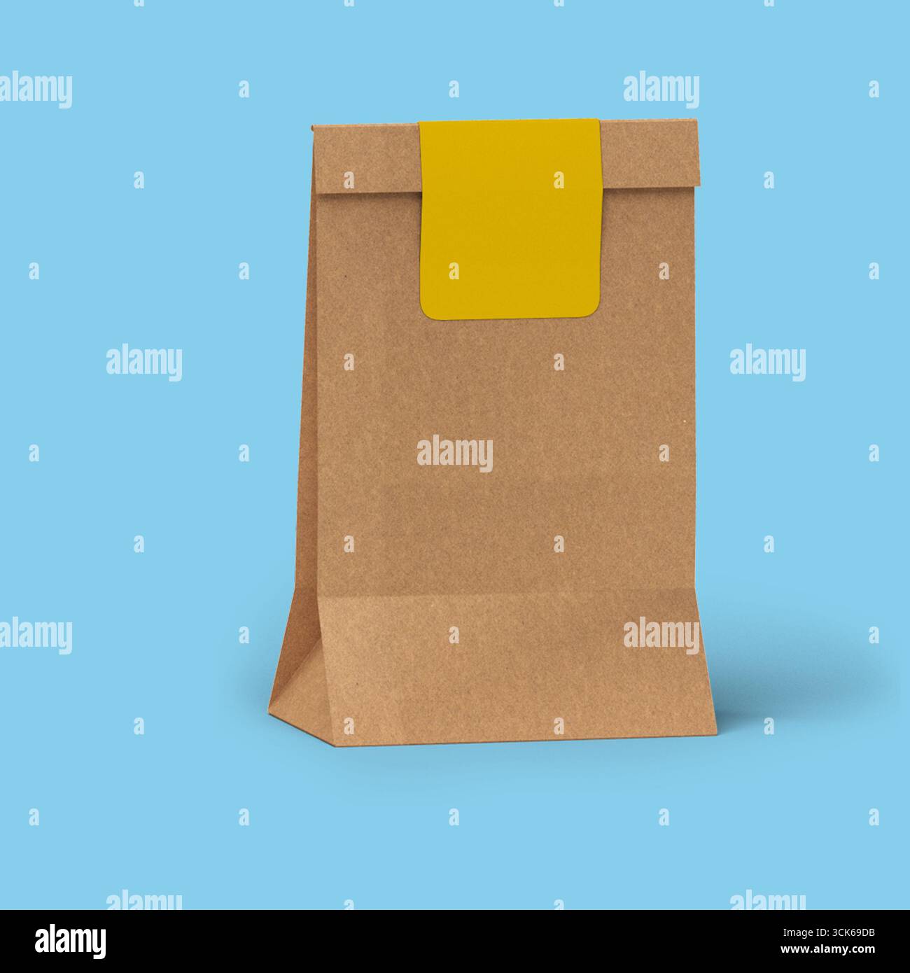 Un semplice sacchetto di carta marrone con un adesivo giallo sulla parte superiore, spesso utilizzato per confezionare alimenti o articoli da asporto. Foto Stock