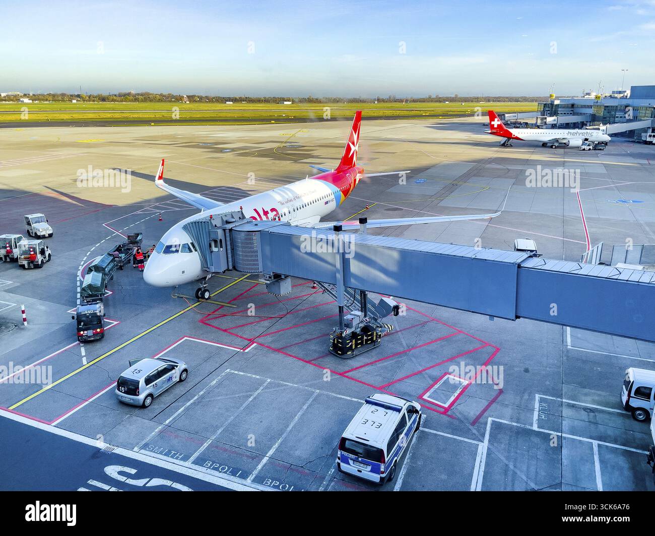 Vista dell'aeromobile passeggeri di Air Malta sul ponte delle dita per l'imbarco sbarcare i passeggeri di fronte all'edificio dell'aeroporto, nel grembiule dello sfondo di Foto Stock