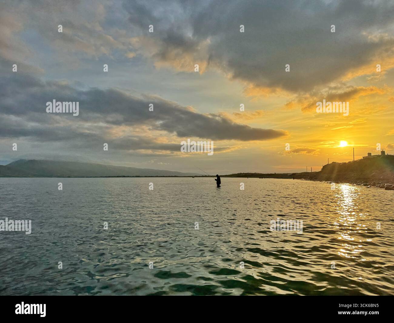Un pescatore pescava in un estuario nella contea di Kerry, nel sud-ovest dell'Irlanda, poco dopo l'alba. Foto Stock