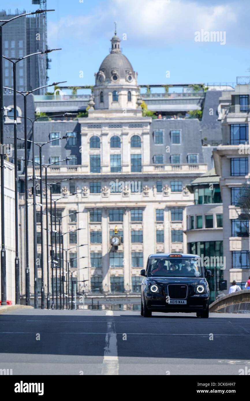 Londra, Regno Unito. Taxi nero che attraversa il London Bridge Foto Stock