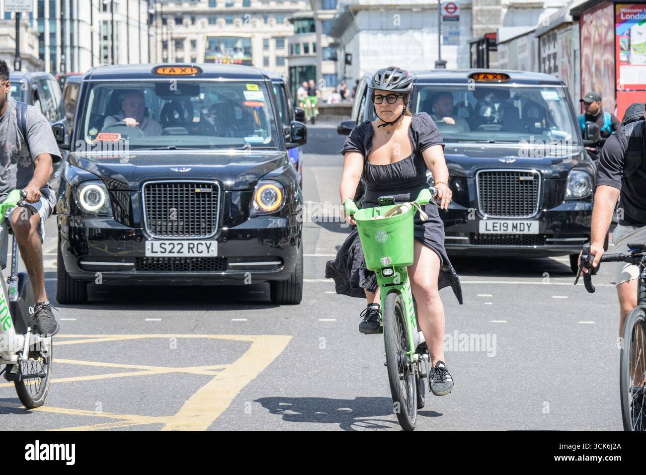 Londra, Regno Unito. Taxi neri di Londra e ciclista su una Lime noleggiata che attraversa il London Bridge, visto da sud. Foto Stock