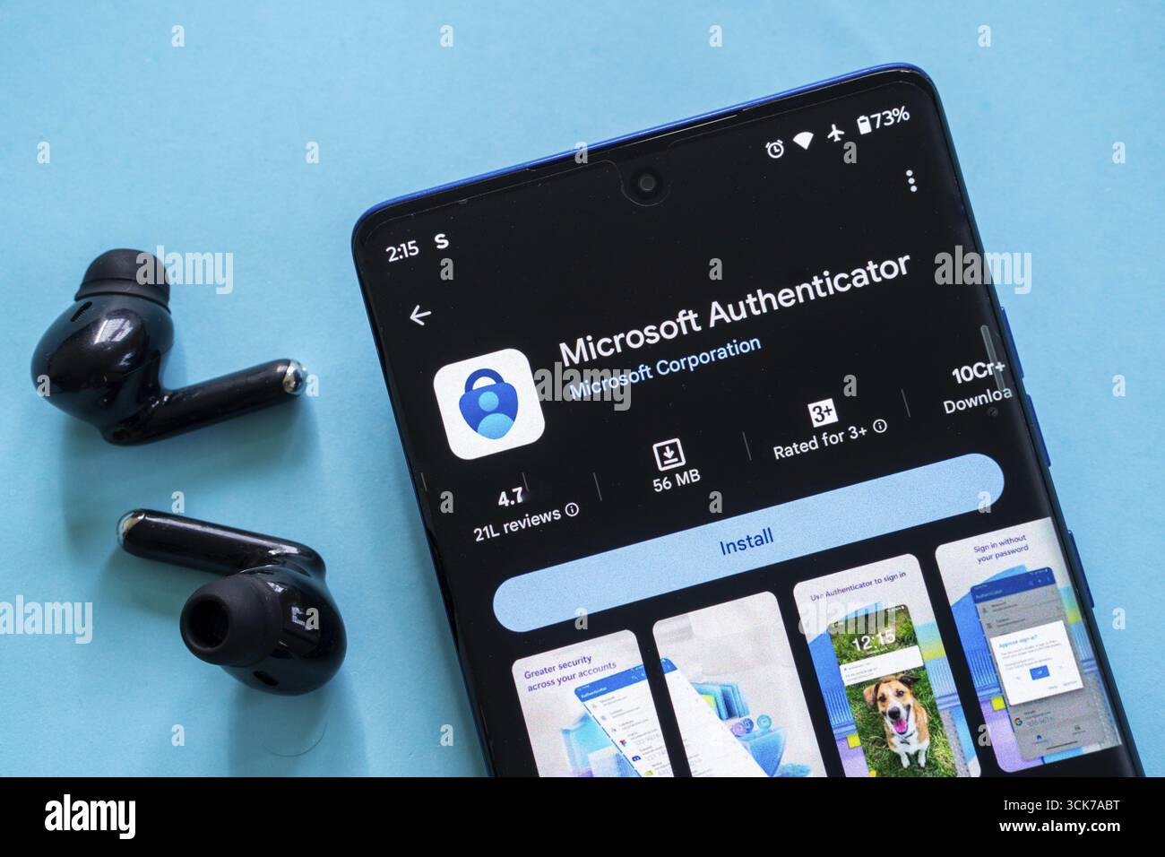Smartphone che visualizza l'app Microsoft Authenticator con auricolari su sfondo blu Foto Stock
