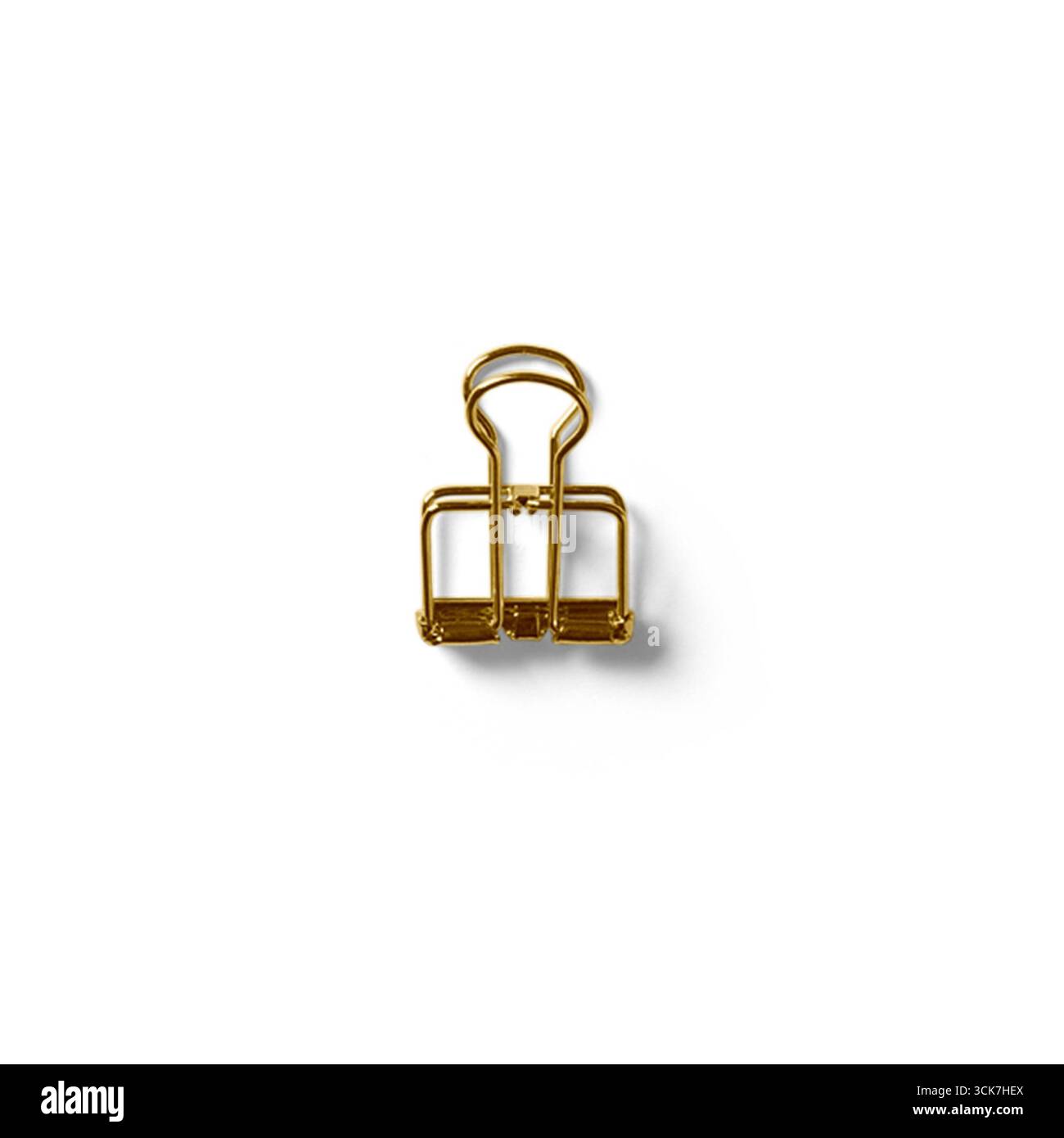 Una clip di legatura in oro, comunemente utilizzata per tenere insieme i fogli di carta. Foto Stock
