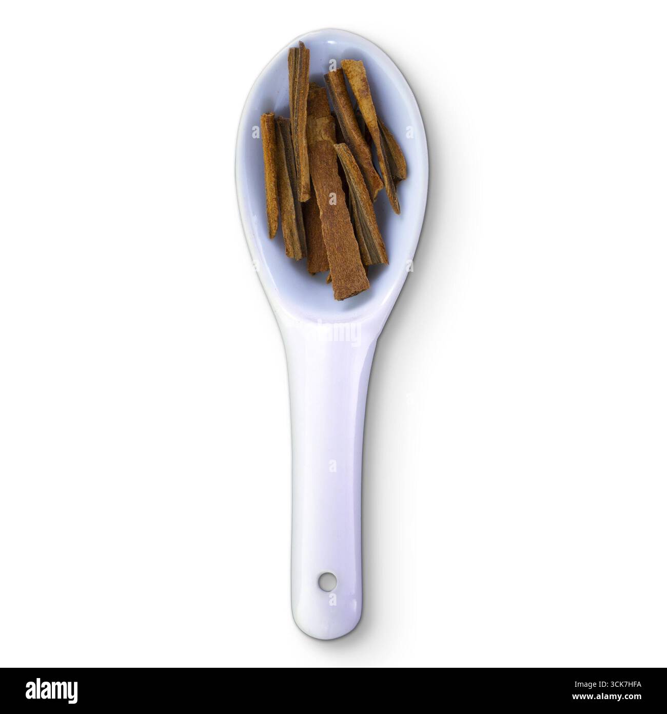 Un cucchiaio bianco contiene diversi pezzi di bastoncini di cannella, mostrando una spezia comune utilizzata per cucinare e cuocere. Foto Stock