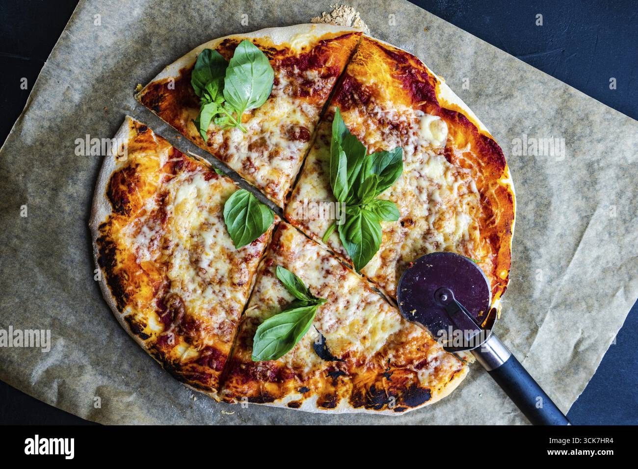 Pizza fatta in casa con foglie di basilico sul tavolo scuro Foto Stock
