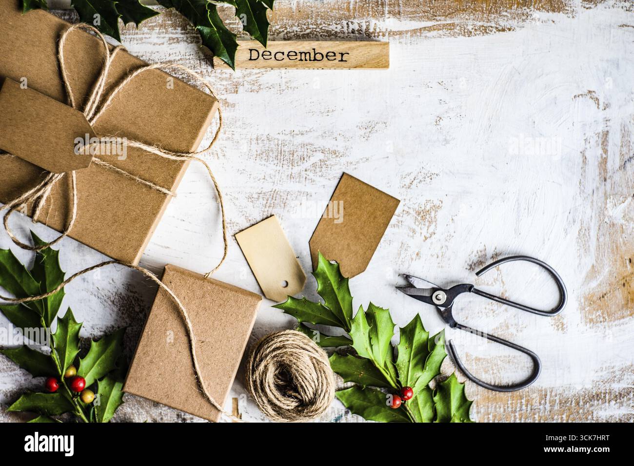 Regalo di Natale su sfondo vintage in legno decorato con piante di agrifoglio Foto Stock