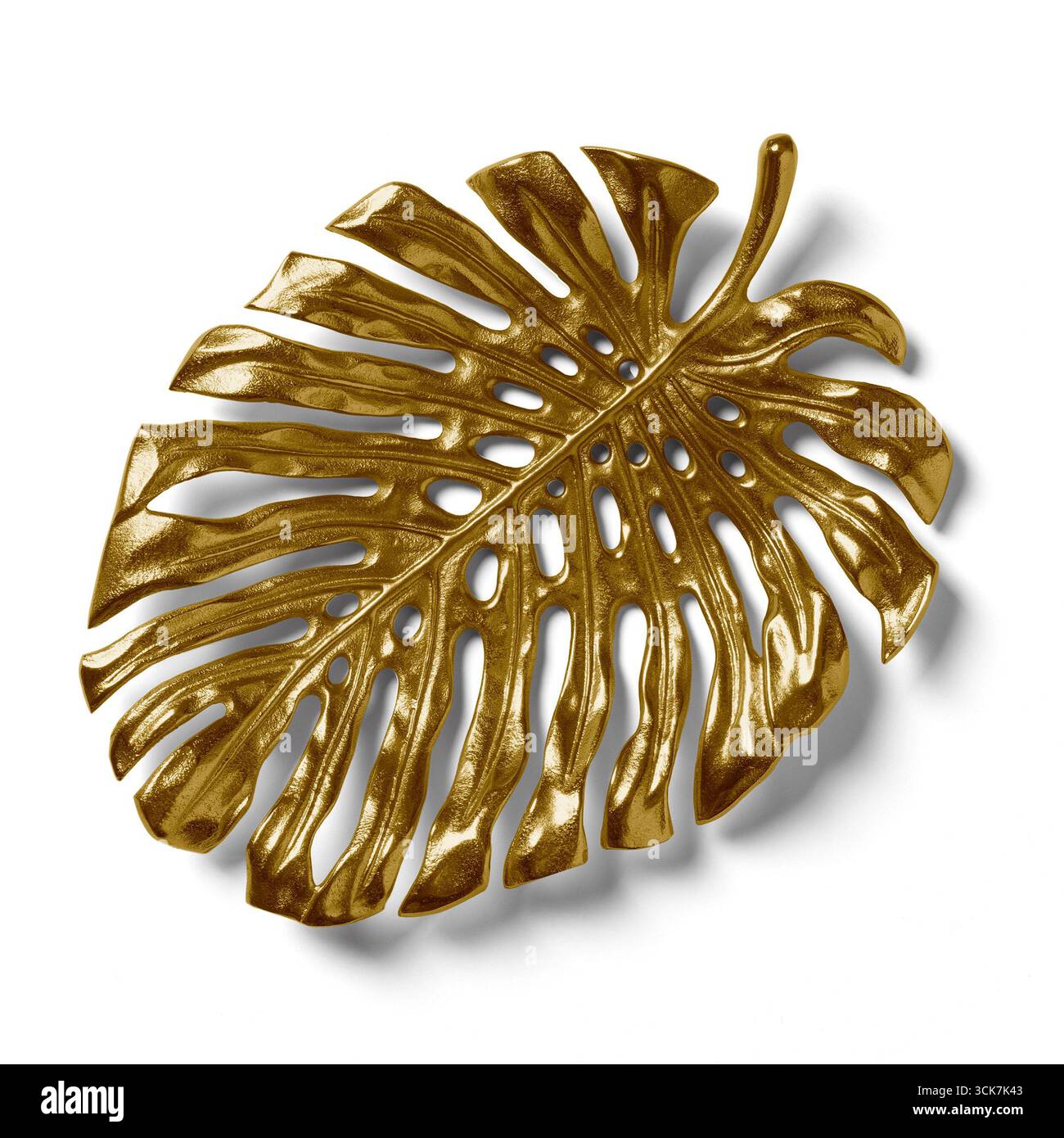 Un pezzo decorativo in foglia di monstera dorata che presenta dettagli intricati e una finitura lucida. Foto Stock