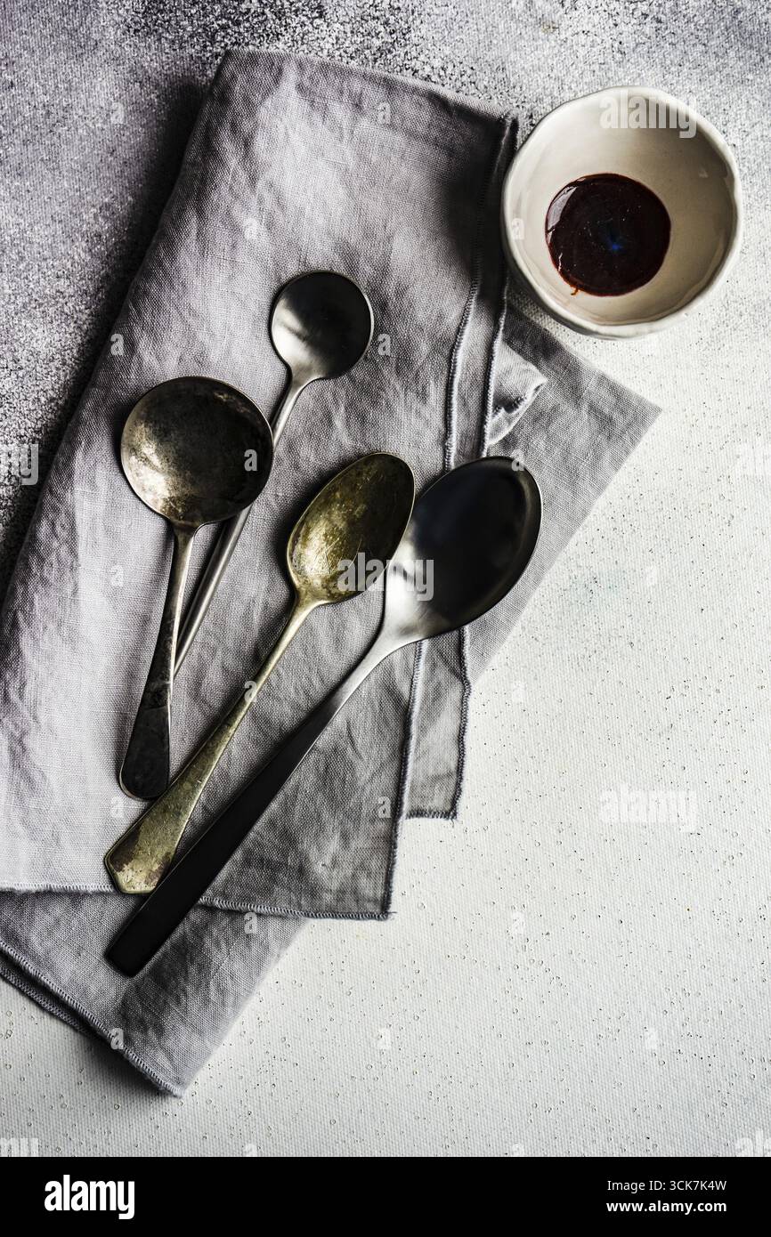 Posate con prua e cucchiai su fondo in cemento colore grigio polvere Foto Stock