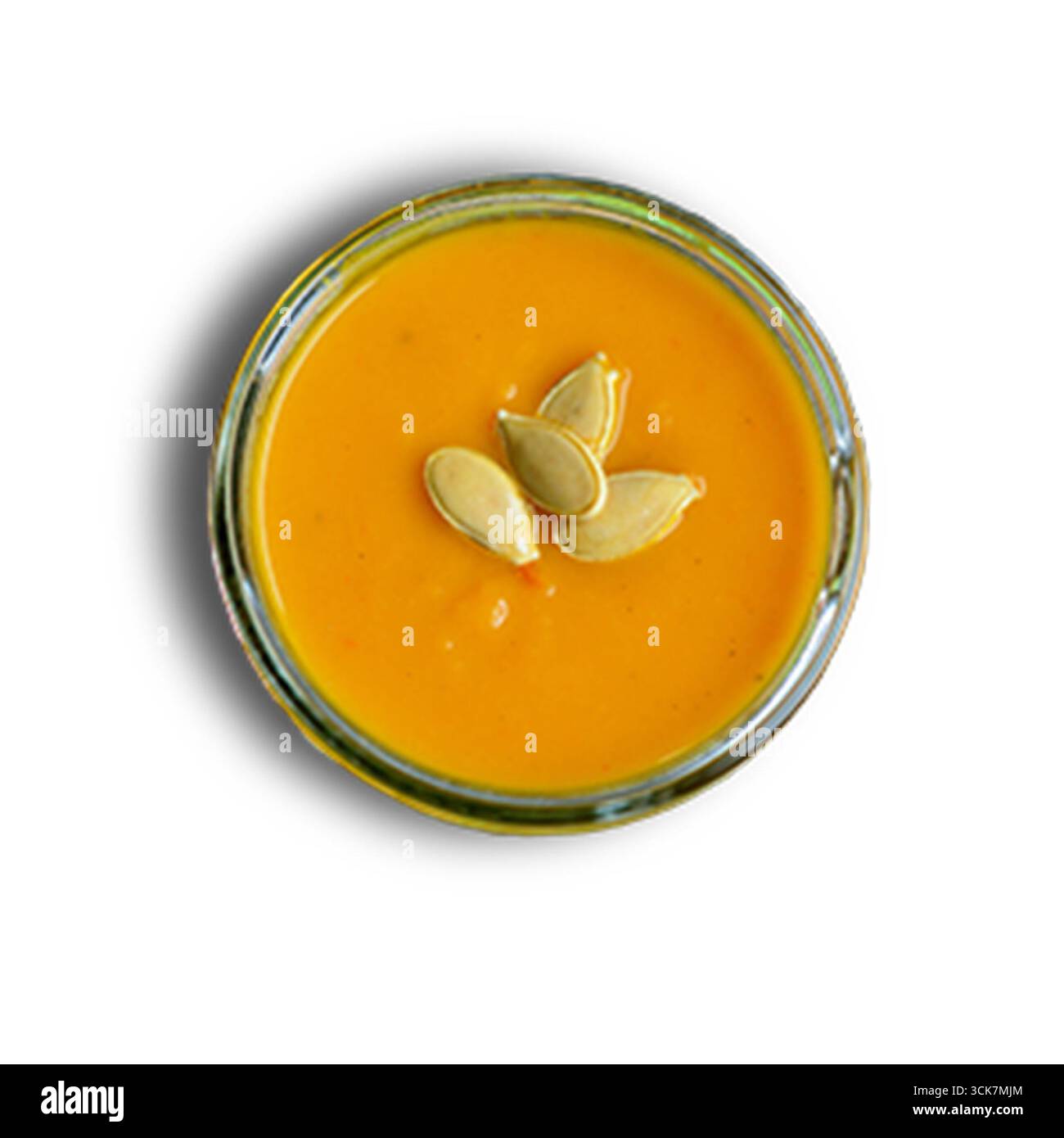 Un piccolo vaso di vetro riempito con purea di arancia liscia e ricoperto di semi di zucca. Foto Stock