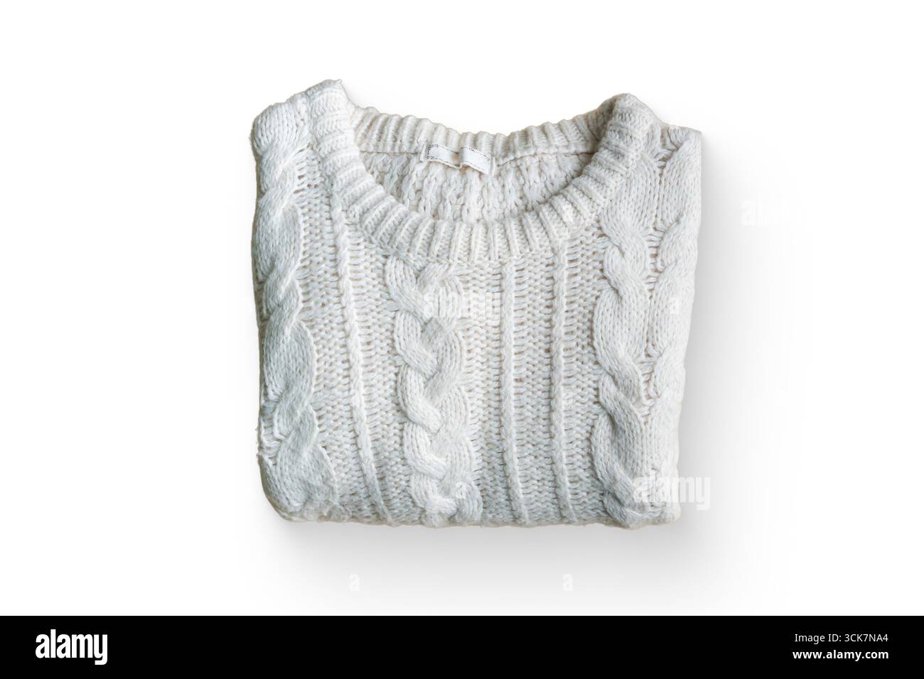 Un pullover in maglia a cavo bianca piegata con cura su uno sfondo semplice. Foto Stock